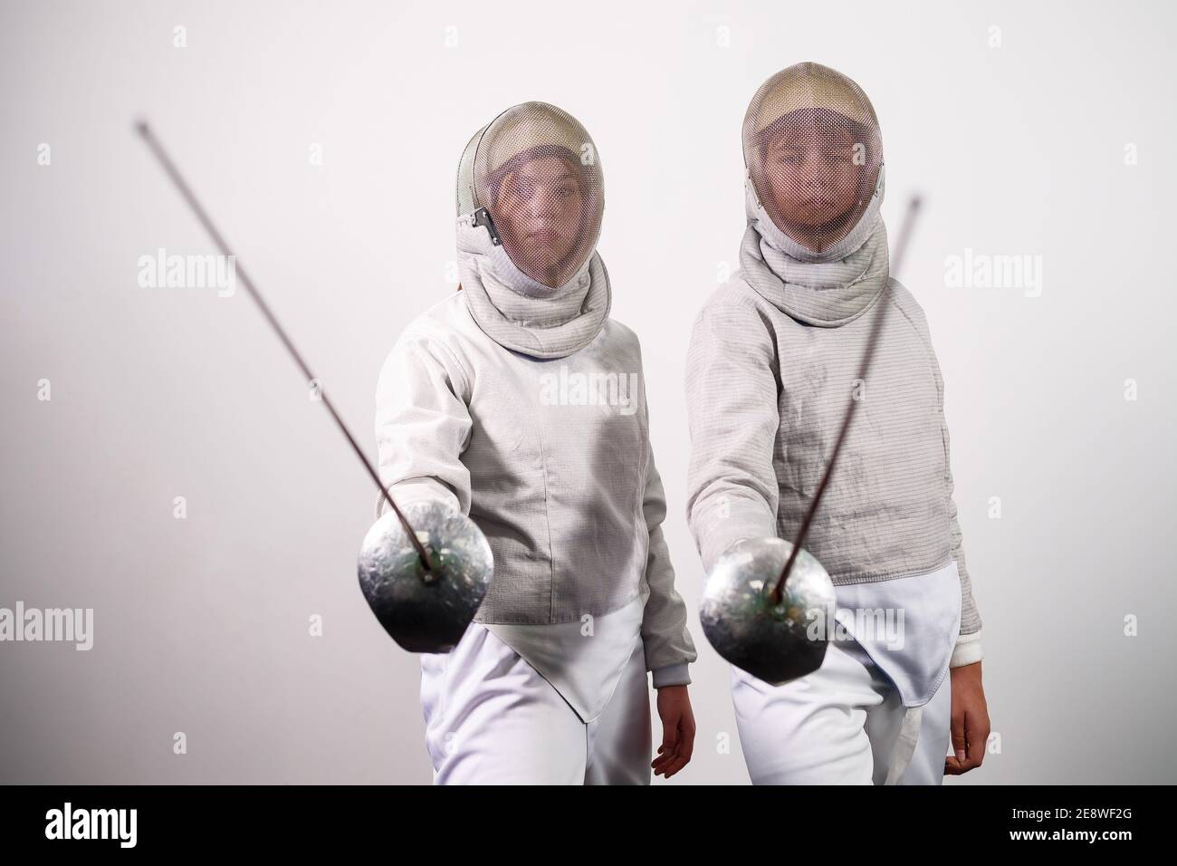 Teenage girls in fencing costumes with swords in their hands isolated