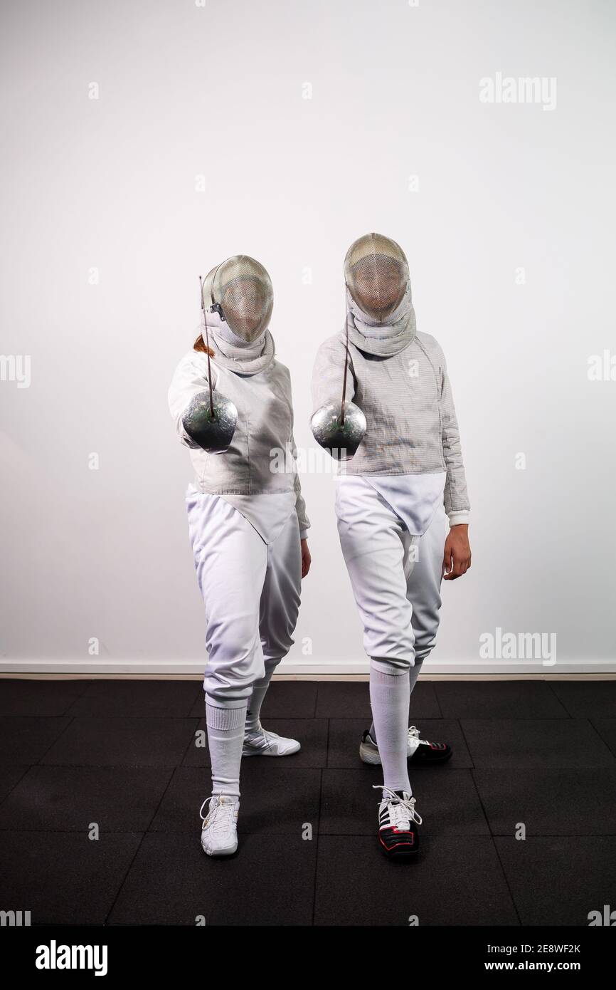 Teenage girls in fencing costumes with swords in their hands isolated