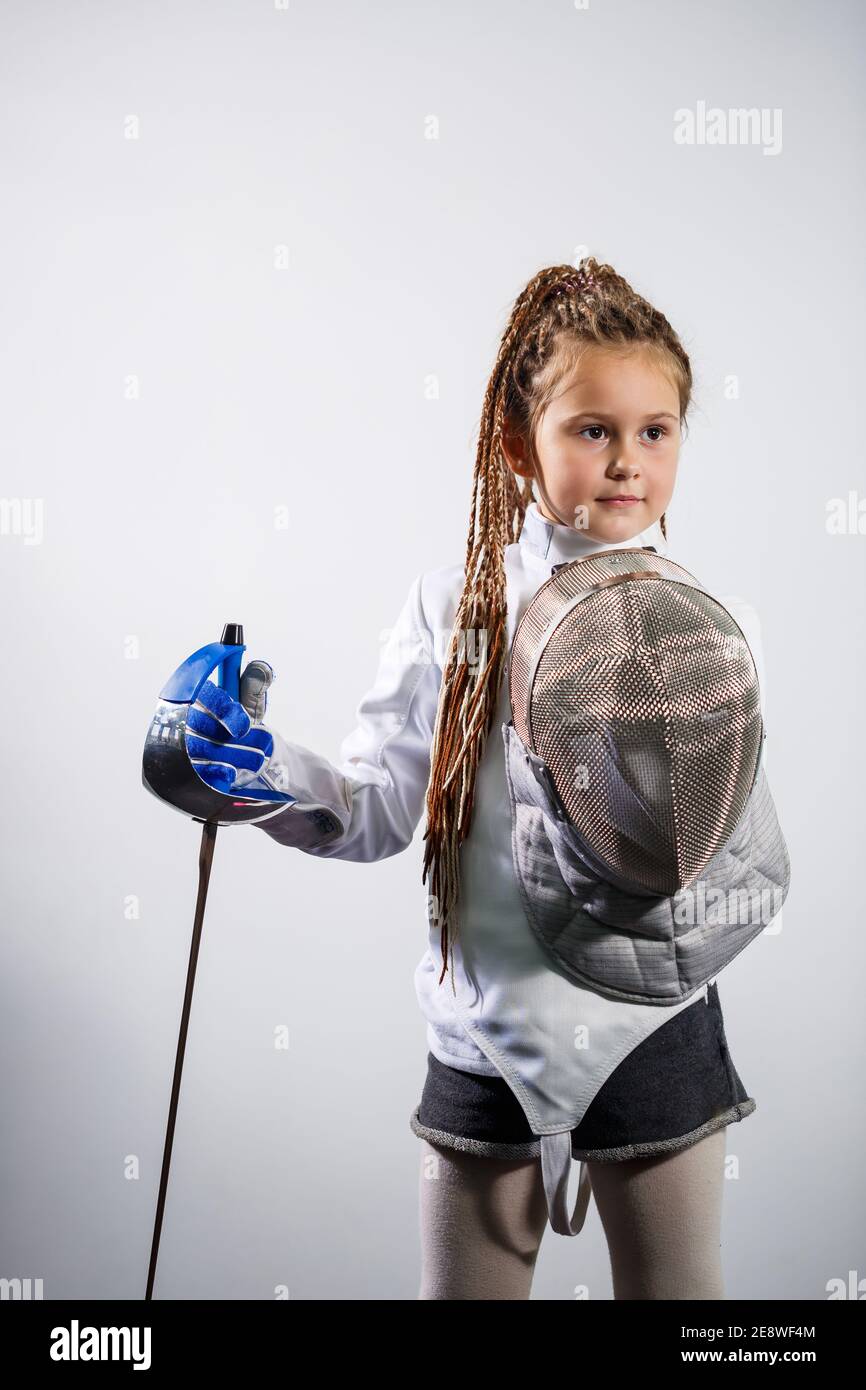 A child in a fencing costume is holding an epee. Girl learning fencing Stock Photo