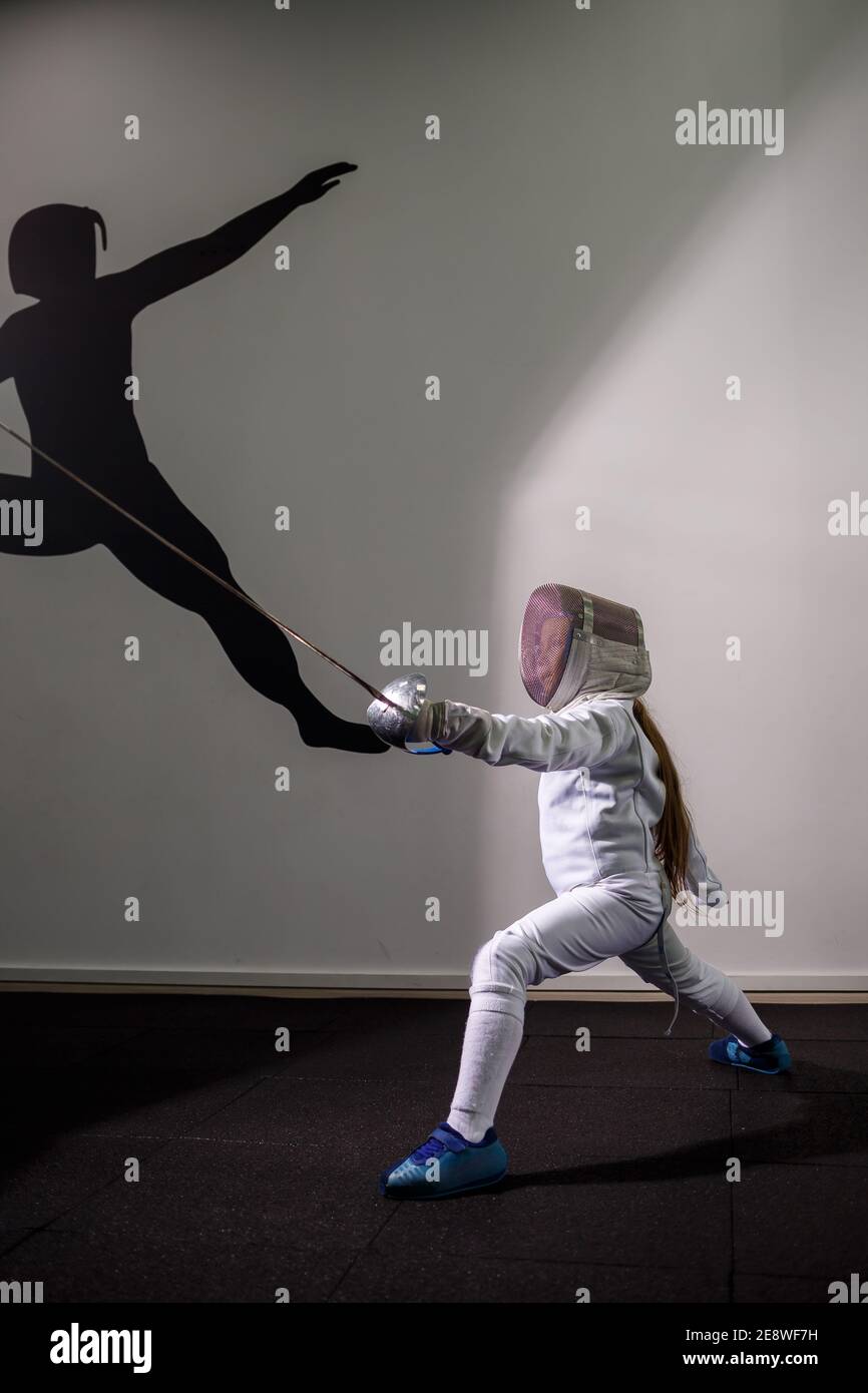 A girl in a fencing suit with a sword in hand. Young female model  practicing and exercising. Sports, healthy lifestyle Stock Photo - Alamy