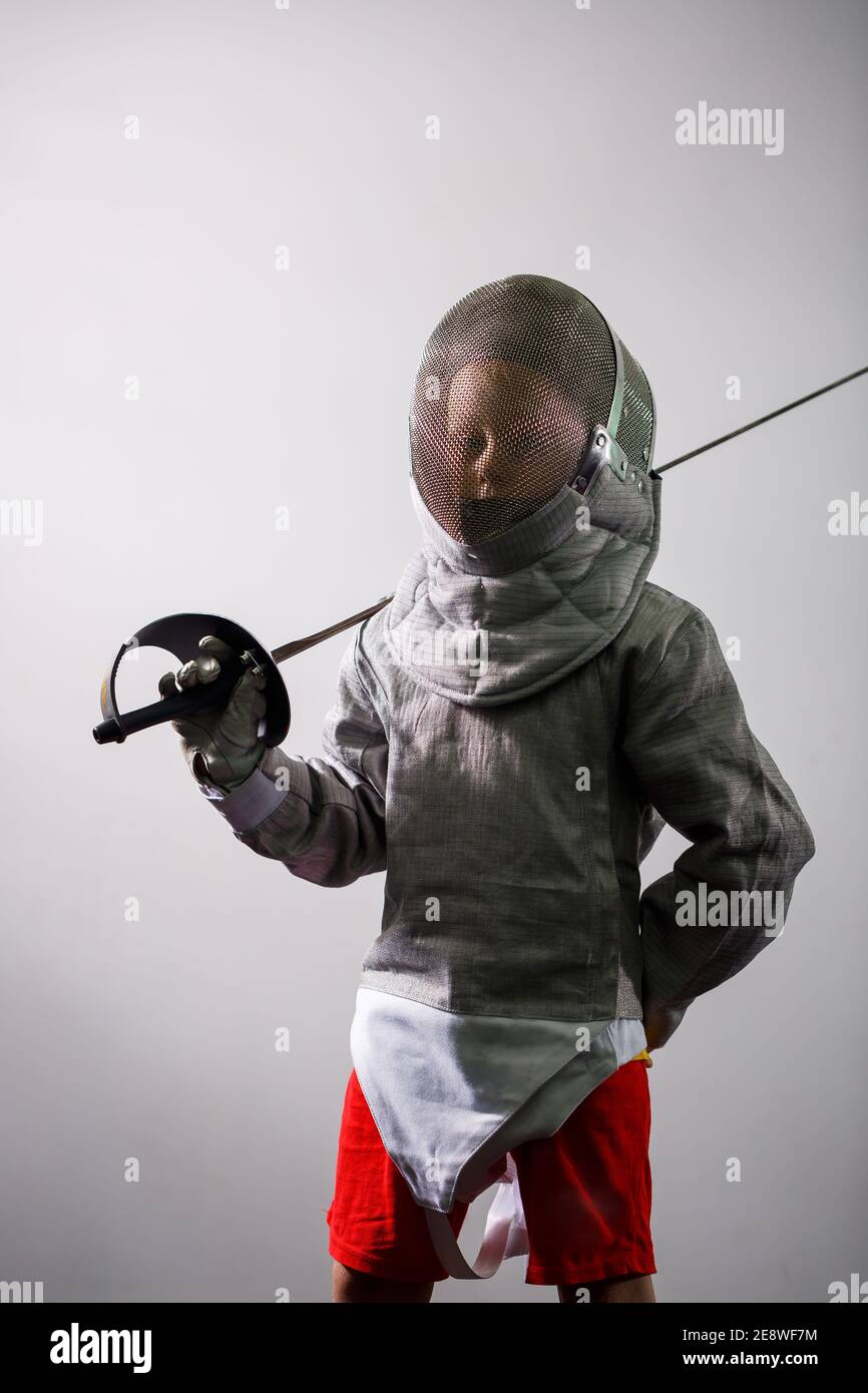 A girl in a fencing suit with a sword in hand. Young female model practicing and exercising. Sports, healthy lifestyle. Stock Photo