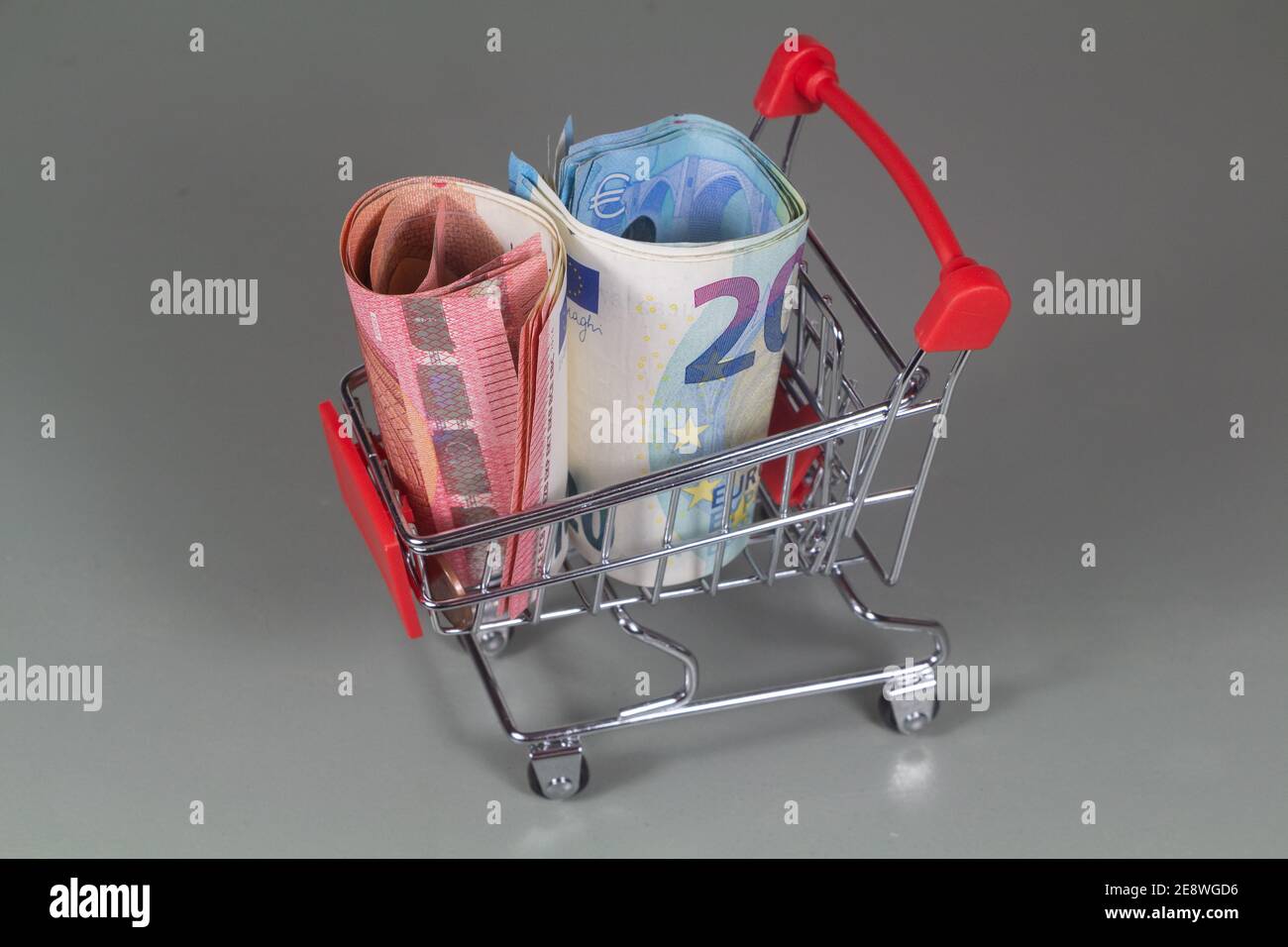Small shopping cart and banknotes of ten and twenty euros Stock Photo
