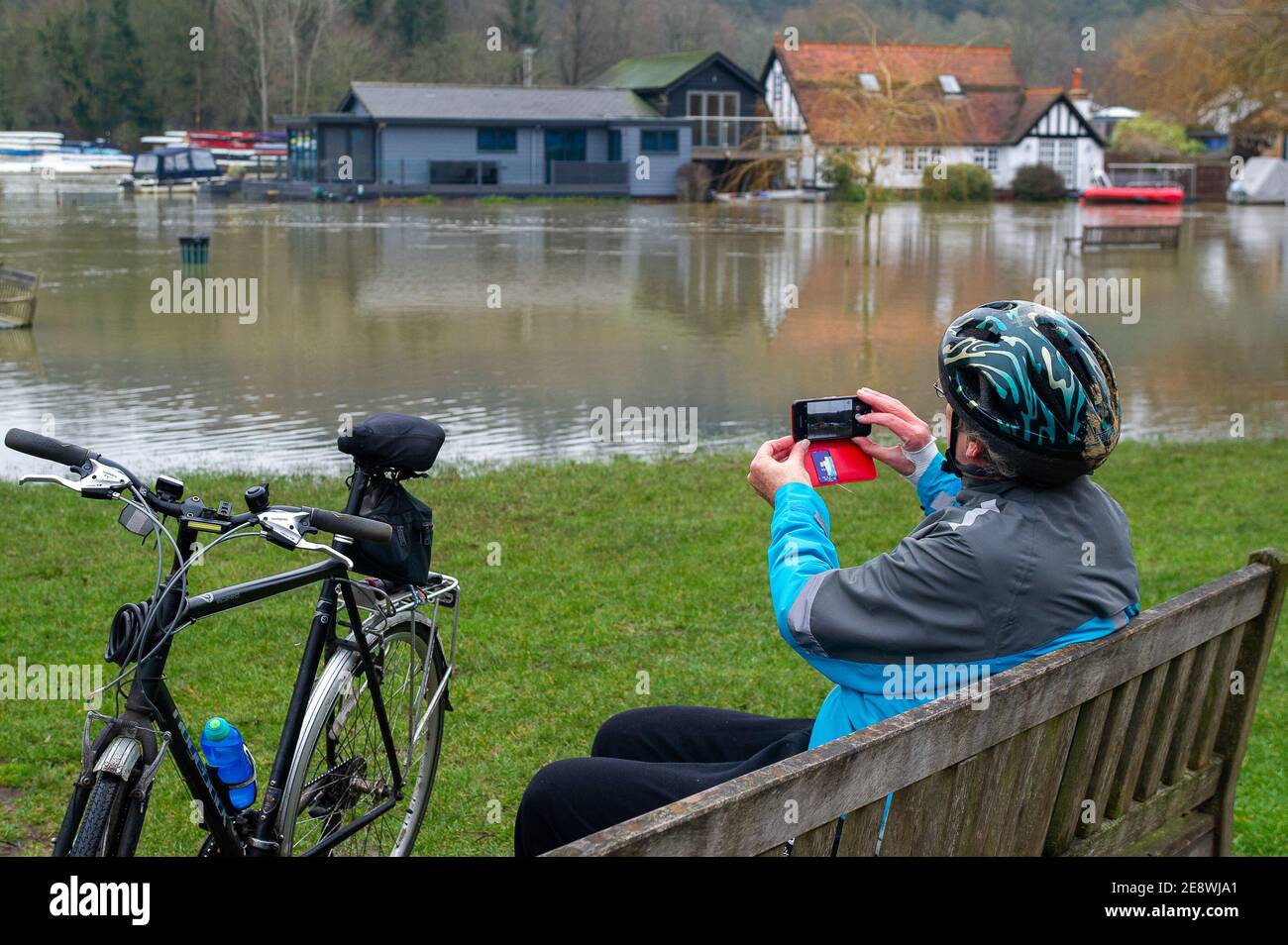 Henley-on-Thames, Oxfordshire, UK. 1st February, 2021. A cyclist stops to take a photo of the flooding. A flood warning is in place for the River Thames at Henley. Property flooding is expected to continue today and those living near the River Thames have been asked to activate their flood barriers. Many of the fields used for the famous Henley Royal Regatta are now under water. Credit: Maureen McLean/Alamy Live News Stock Photo