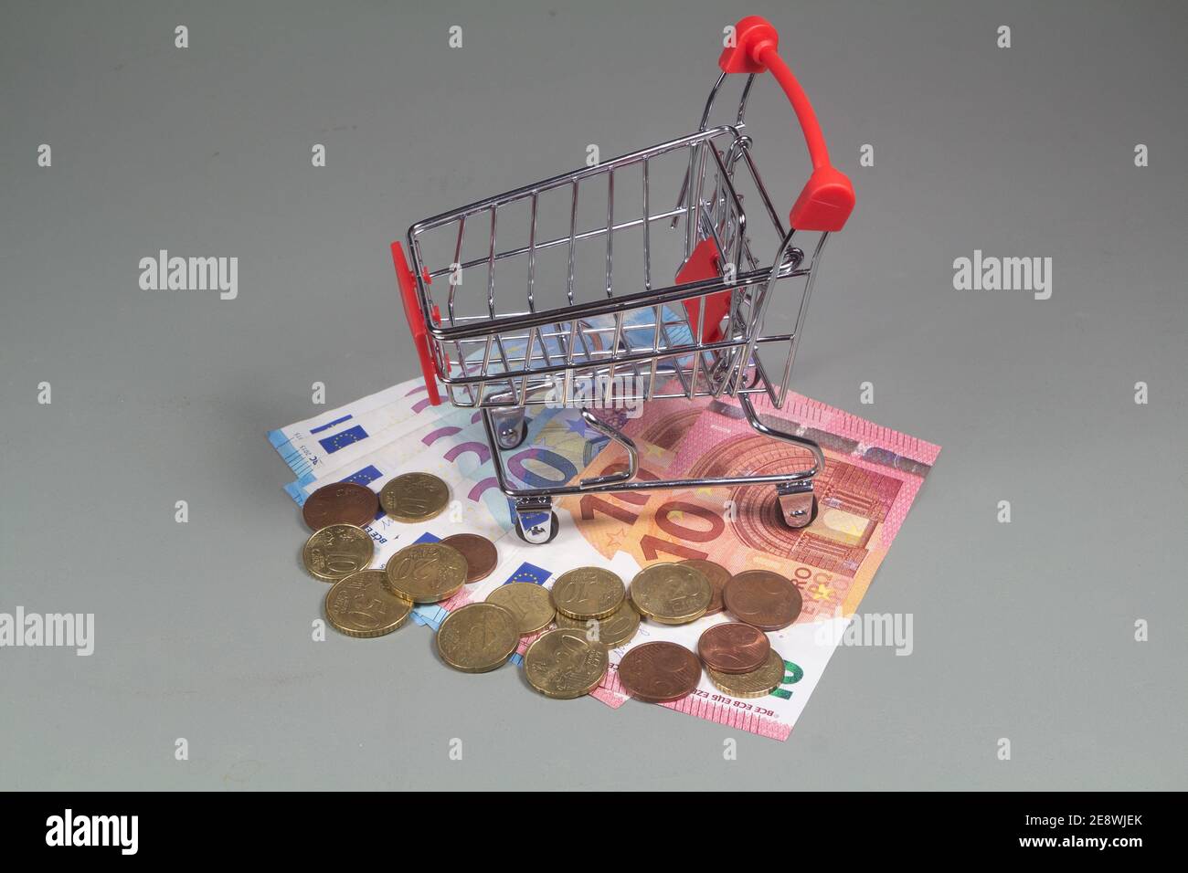 Small shopping cart, euros coins and banknotes Stock Photo