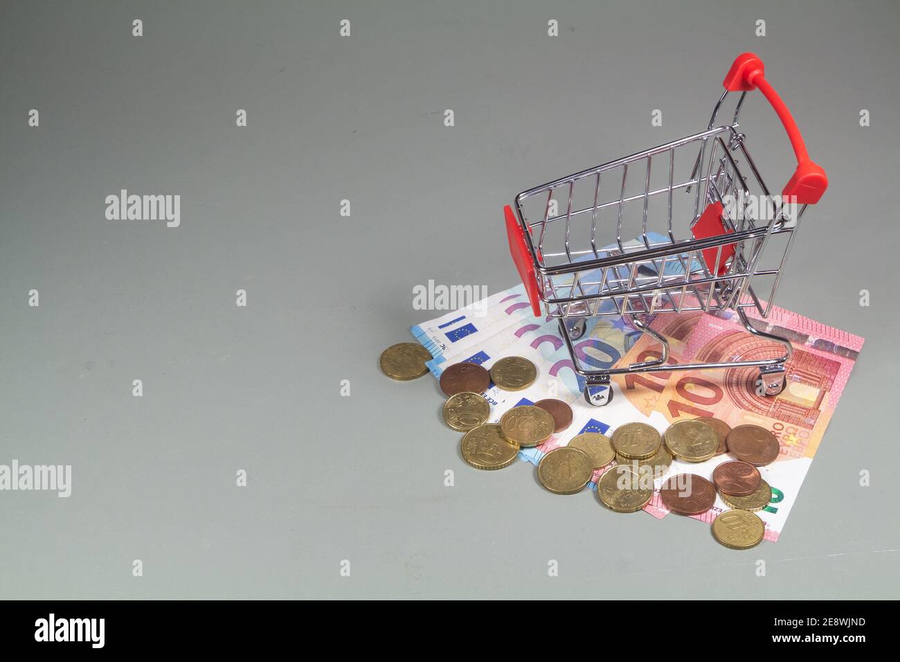 Small shopping cart, euros coins and banknotes Stock Photo
