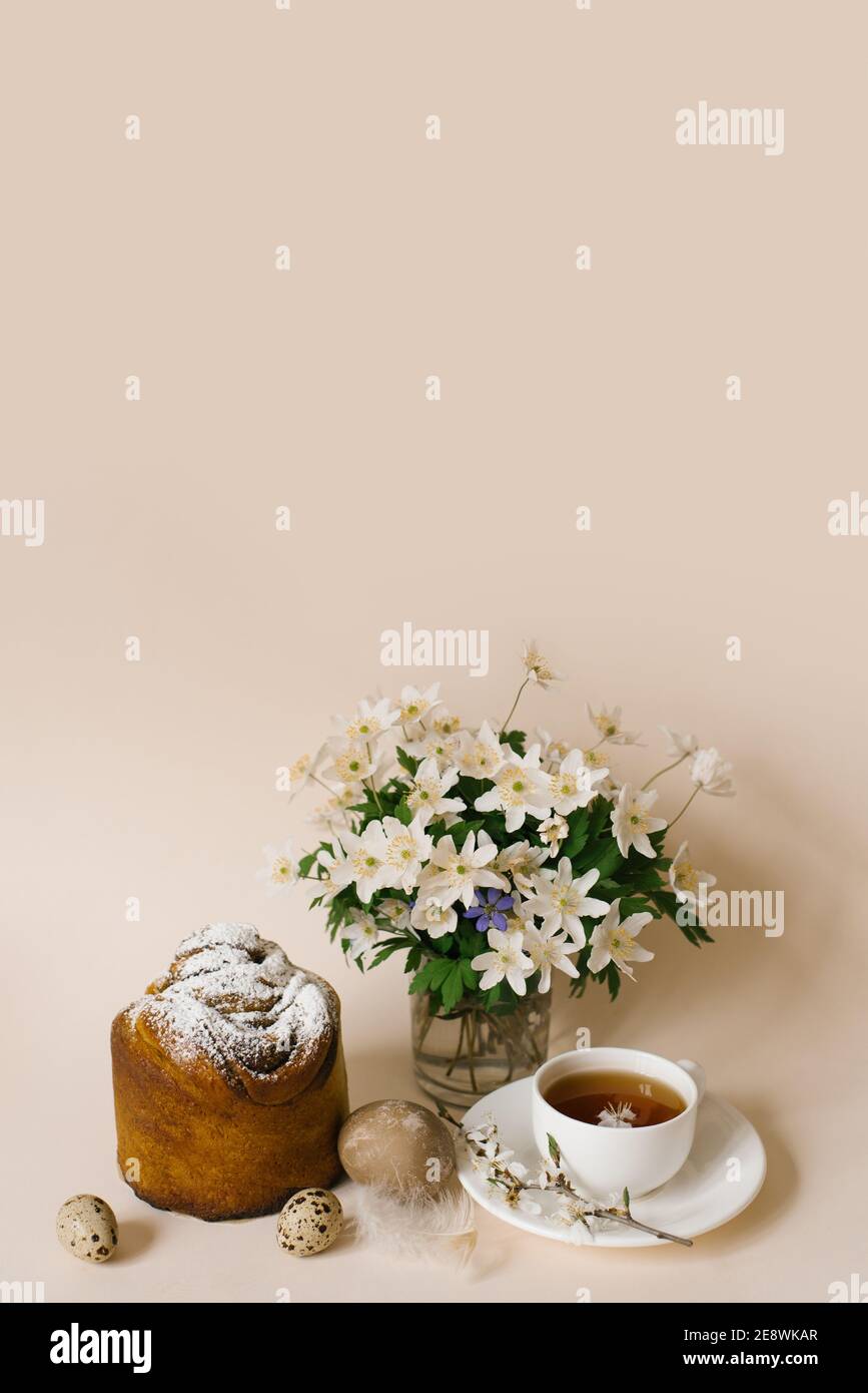 Easter composition with kulich and eggs with spring flowers on beige background. Easter holidays breakfast concept. Stock Photo