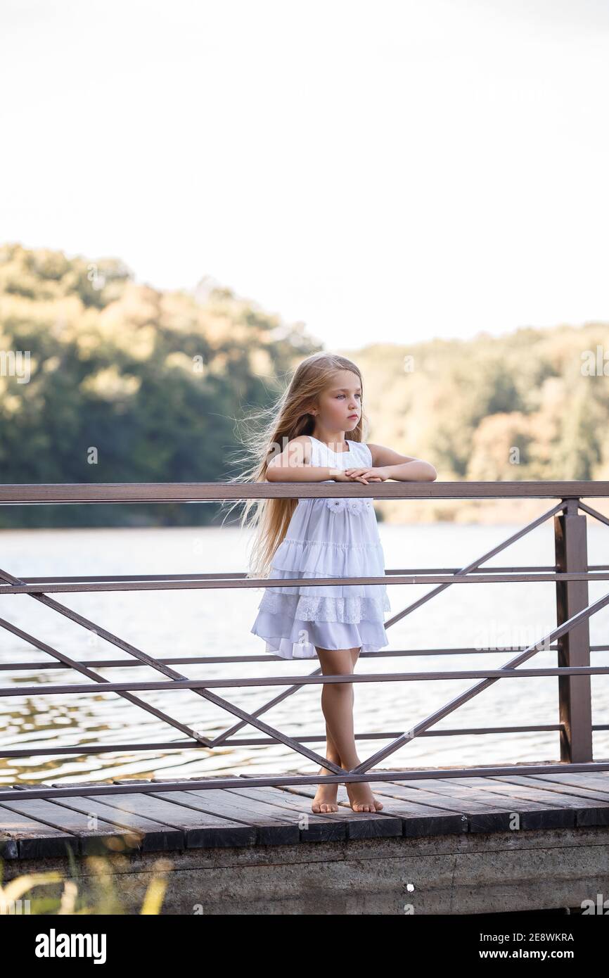 Portrait of a little girl outdoors in the summer by the lake. Little ...