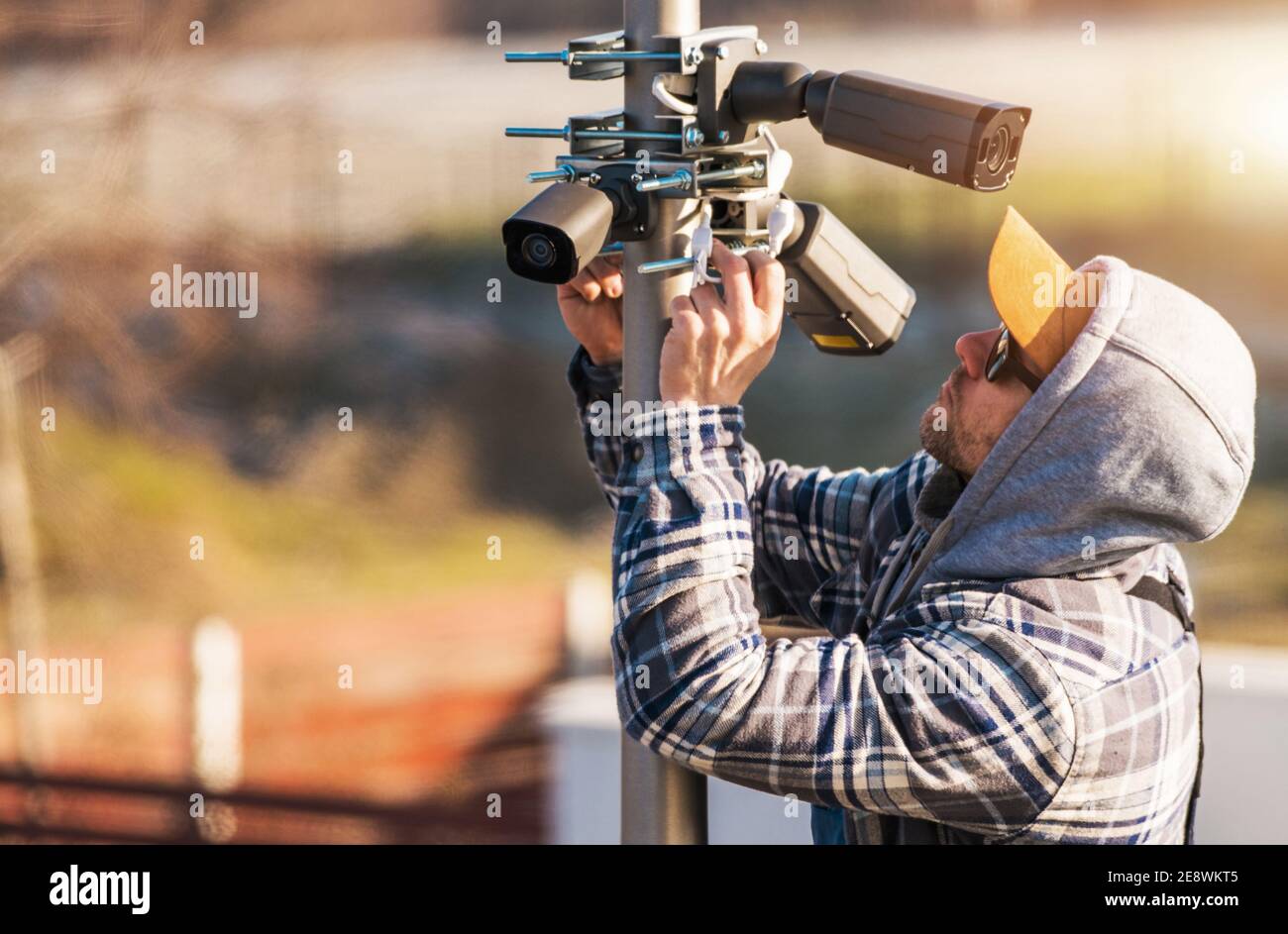 Caucasian CCTV Technician in His 40s Installing IP Cameras on a Pole