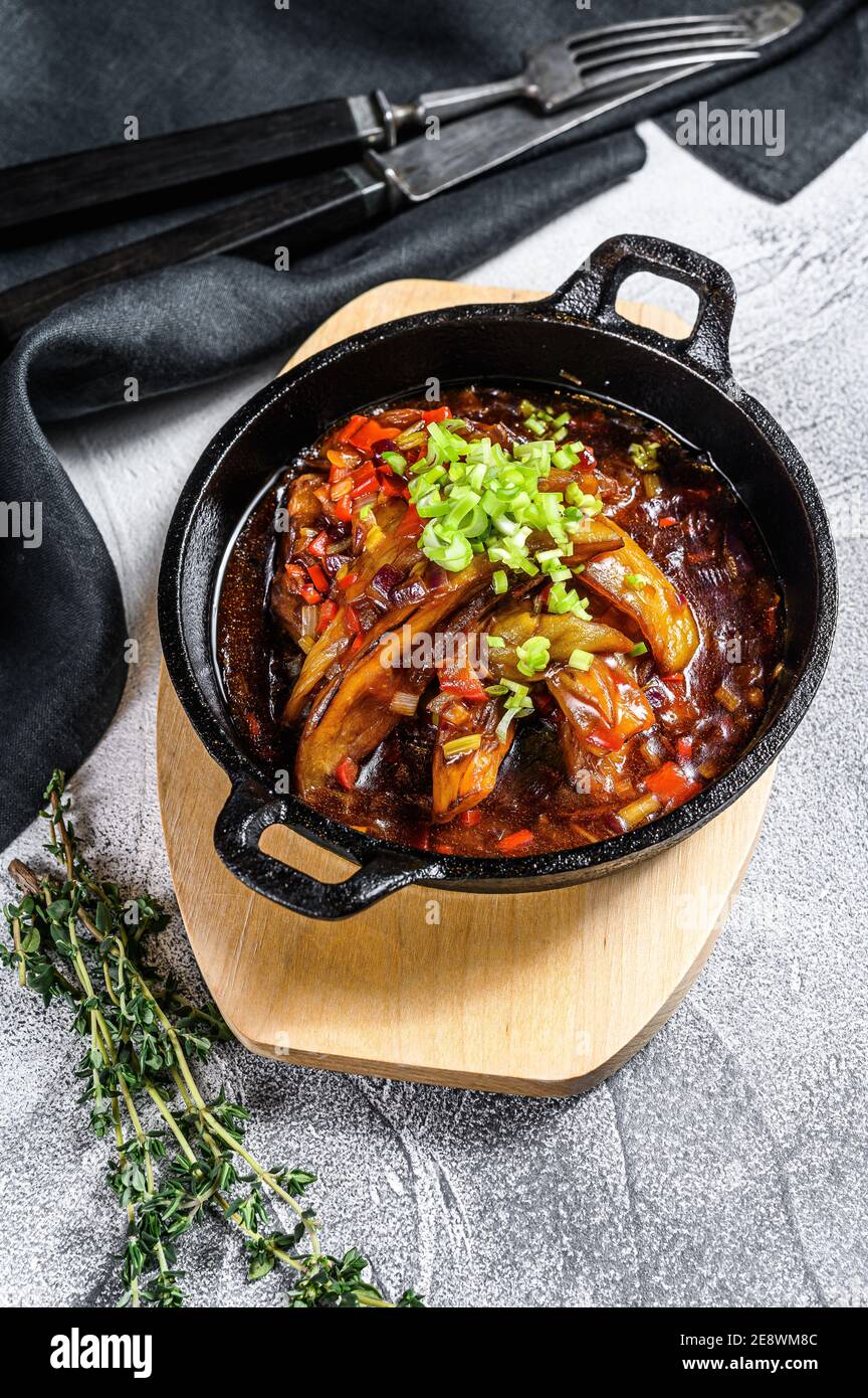 Grilled eggplant in a castiron skillet. Gray background. Top view