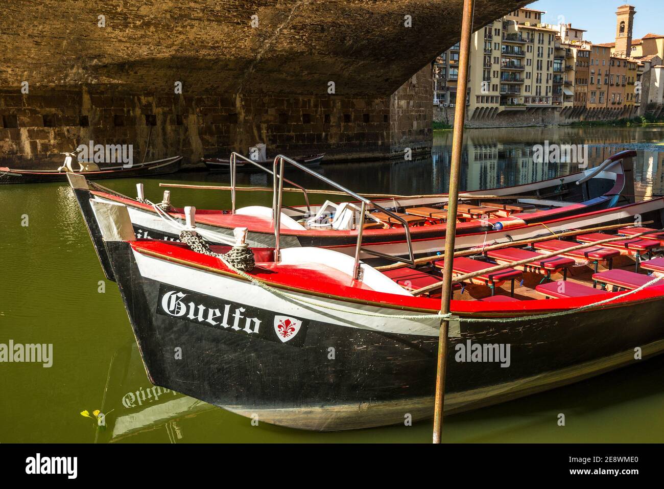 two small colorful boats, named guelfo and ghibellino, belonging to the renaioli of florence parked under the ponte vecchio Stock Photo