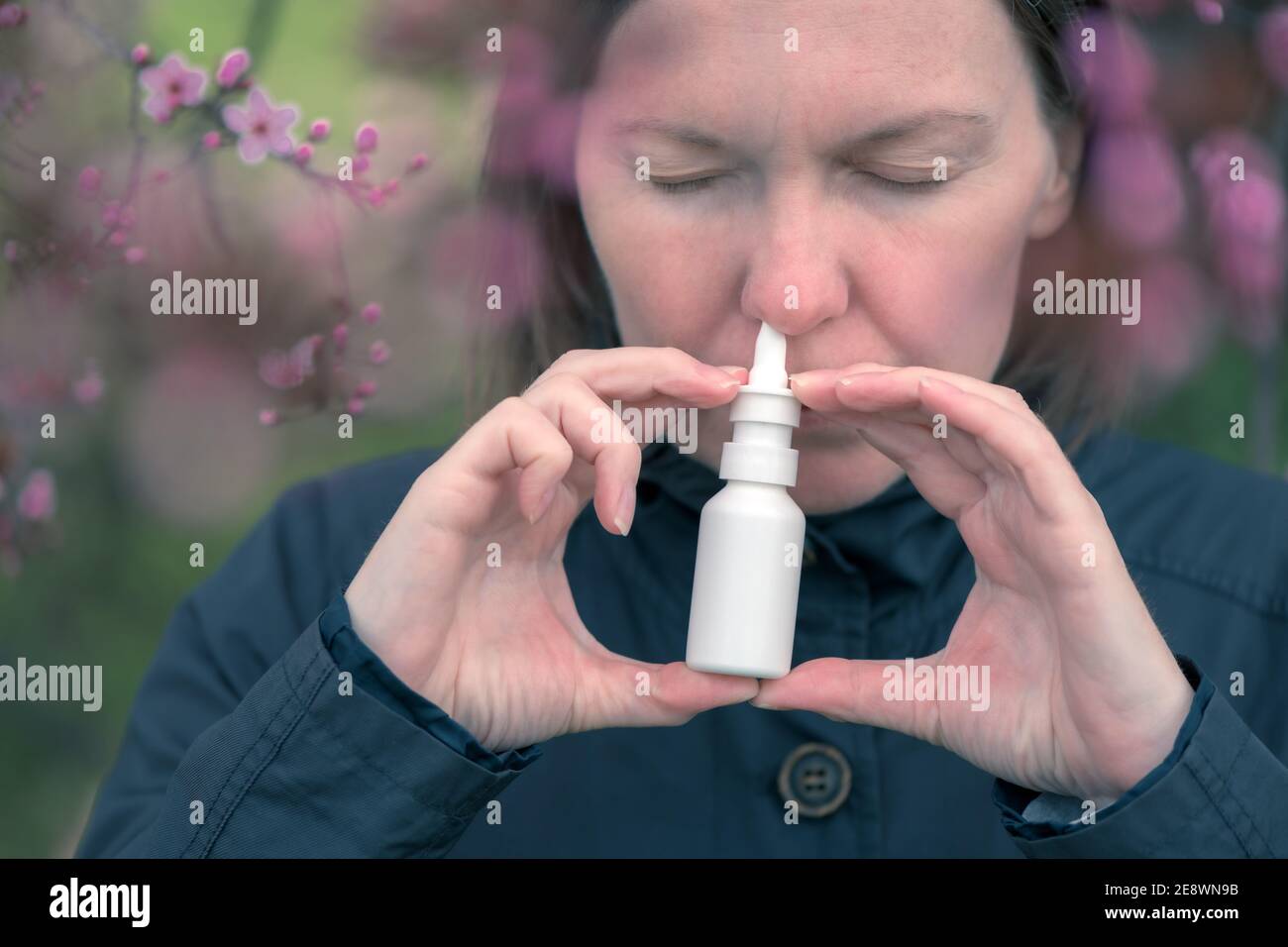 Woman using nasal spray outdoors for tree pollen allergy treatment