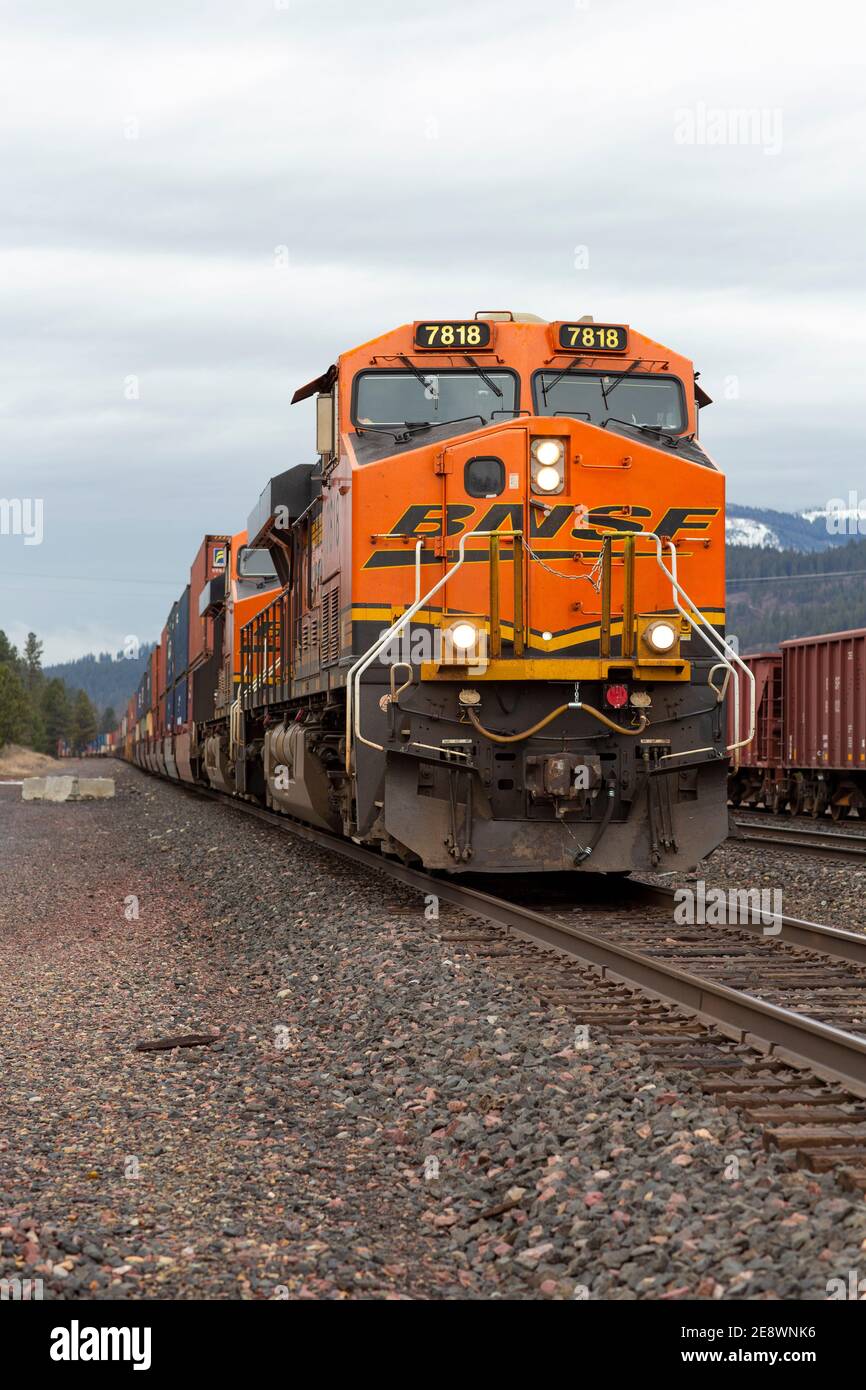 A BNSF train diesel electric locomotive pulling a line of container well cars through the rail yard in Troy, Montana.   Burlington Northern and Santa Stock Photo
