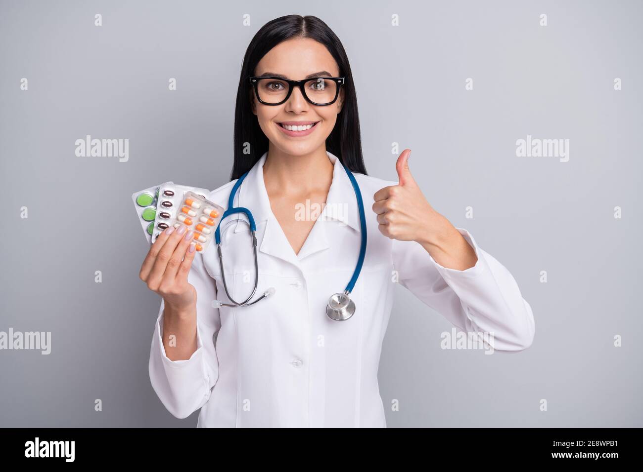 Photo of good mood lady doctor wear white coat eyeglasses showing thumb up holding pain killers