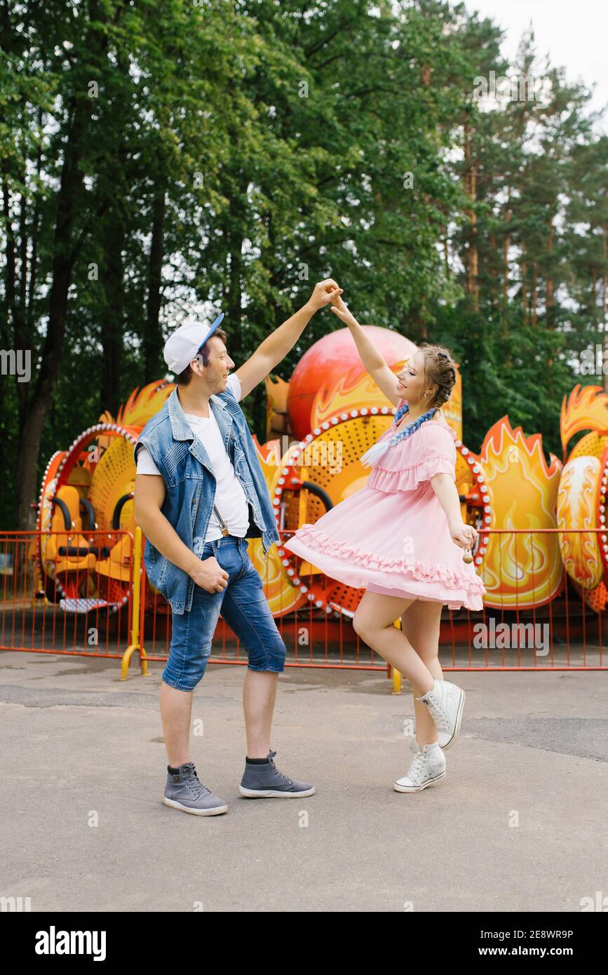 Happy young couple in love having fun in an amusement park and dancing ...