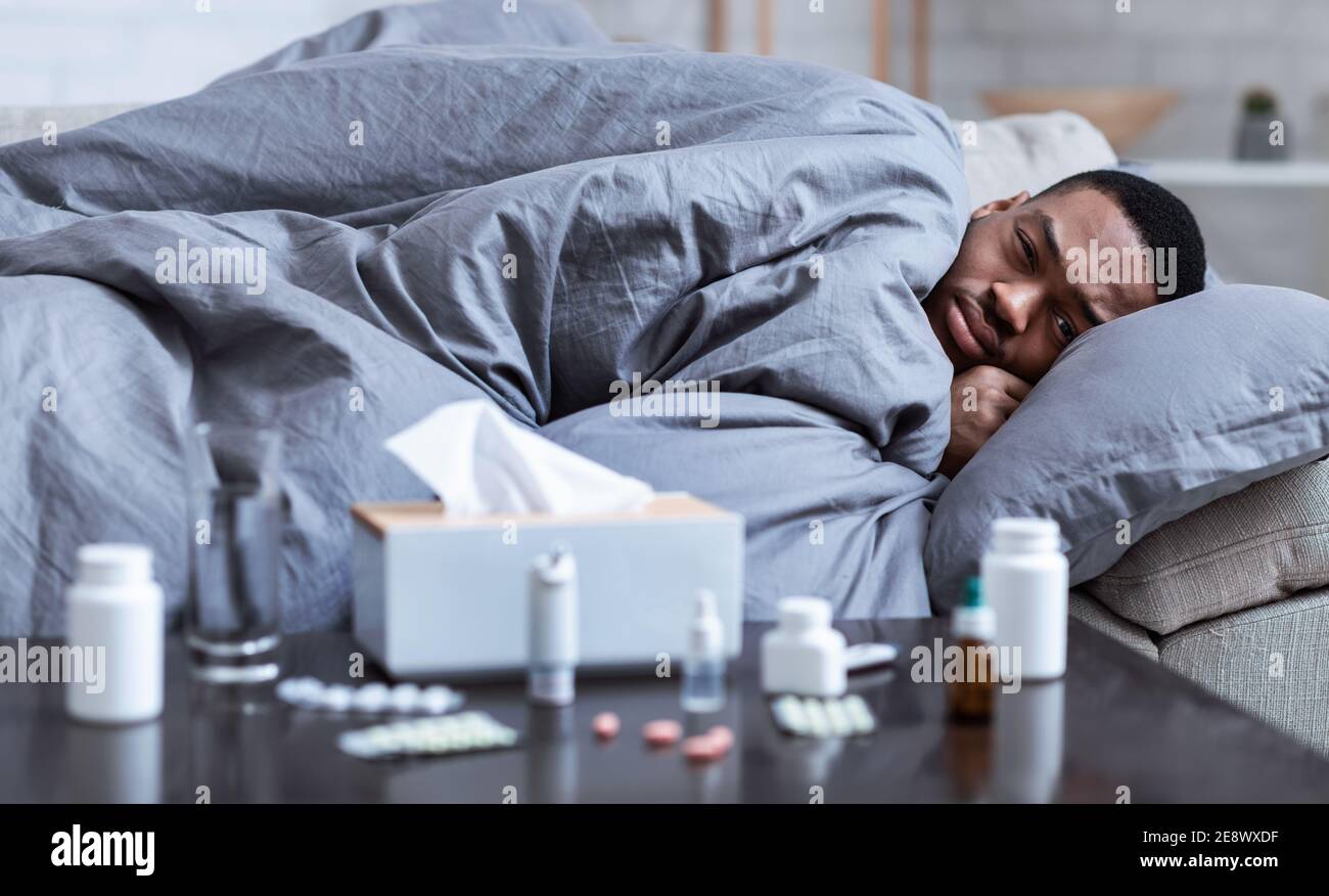 Sick Black Guy Having Chills Lying On Couch At Home Stock Photo