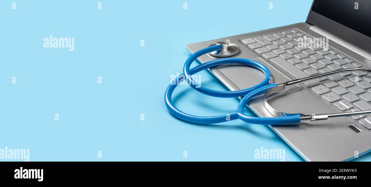 laptop computer pc and medical stethoscope isolated on blue background. Telehealth concept. Online doctor consultation, copy space. banner Stock Photo