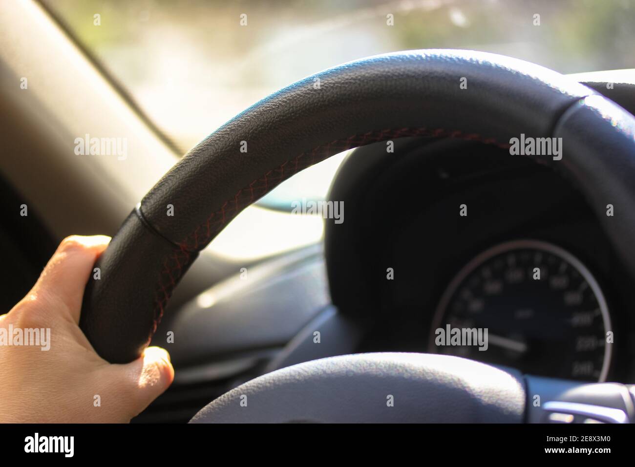 The car driver holds the steering wheel with his hands while driving on