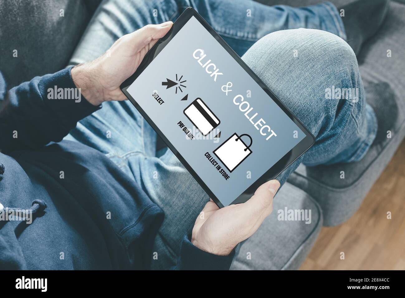 close-up of person on sofa holding tablet computer for online shopping using a click and collect service Stock Photo