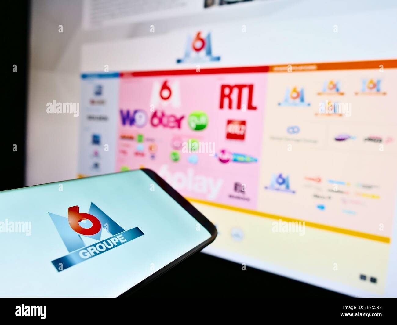 Smartphone with logo of French media holding company Metropole Télévision S.A. (Groupe M6) on display with website. Focus on center of phone screen. Stock Photo