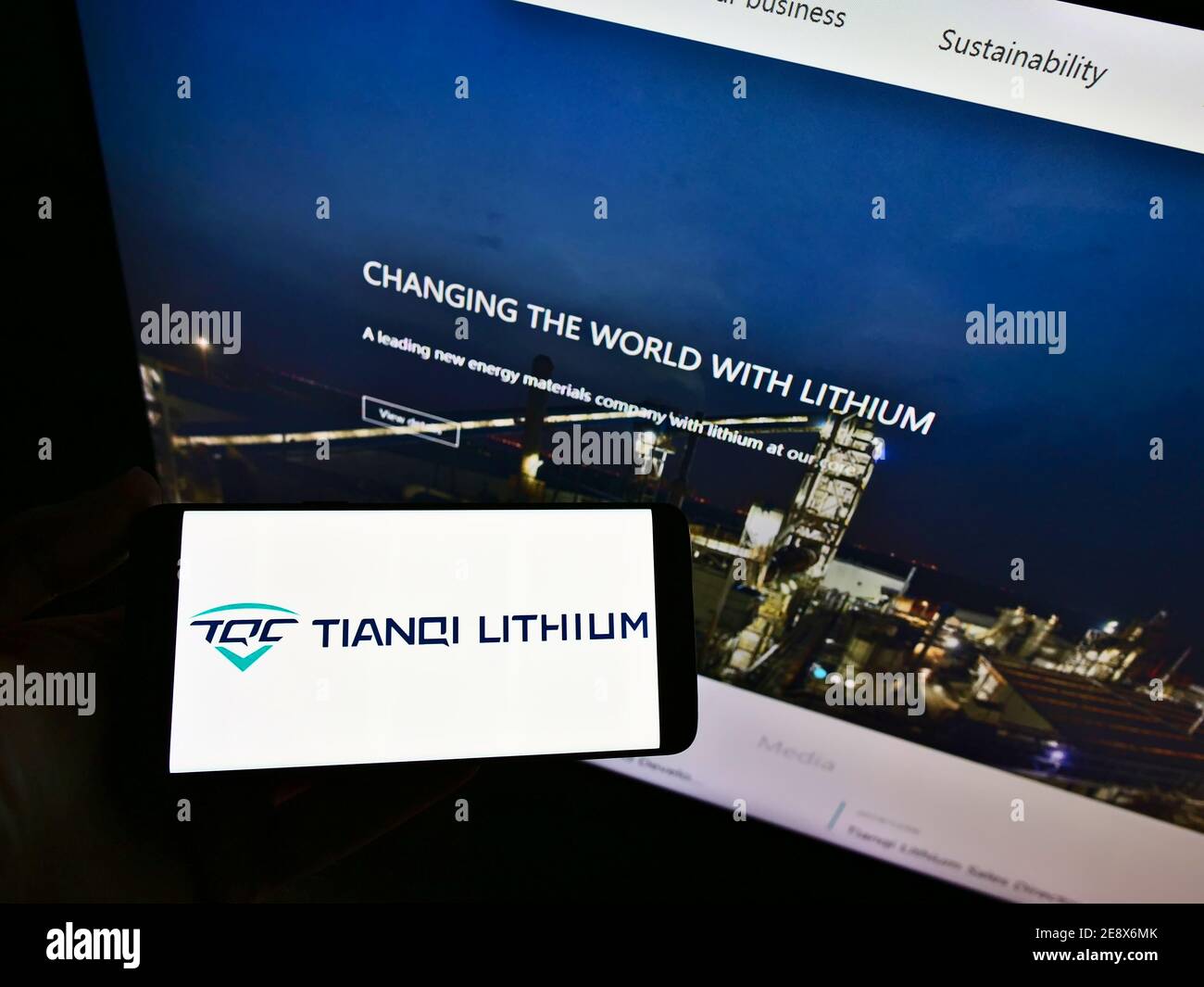 Person holding smartphone with logo of Chinese manufacturing company Tianqi Lithium Corp on display in front of web page. Focus on phone screen. Stock Photo