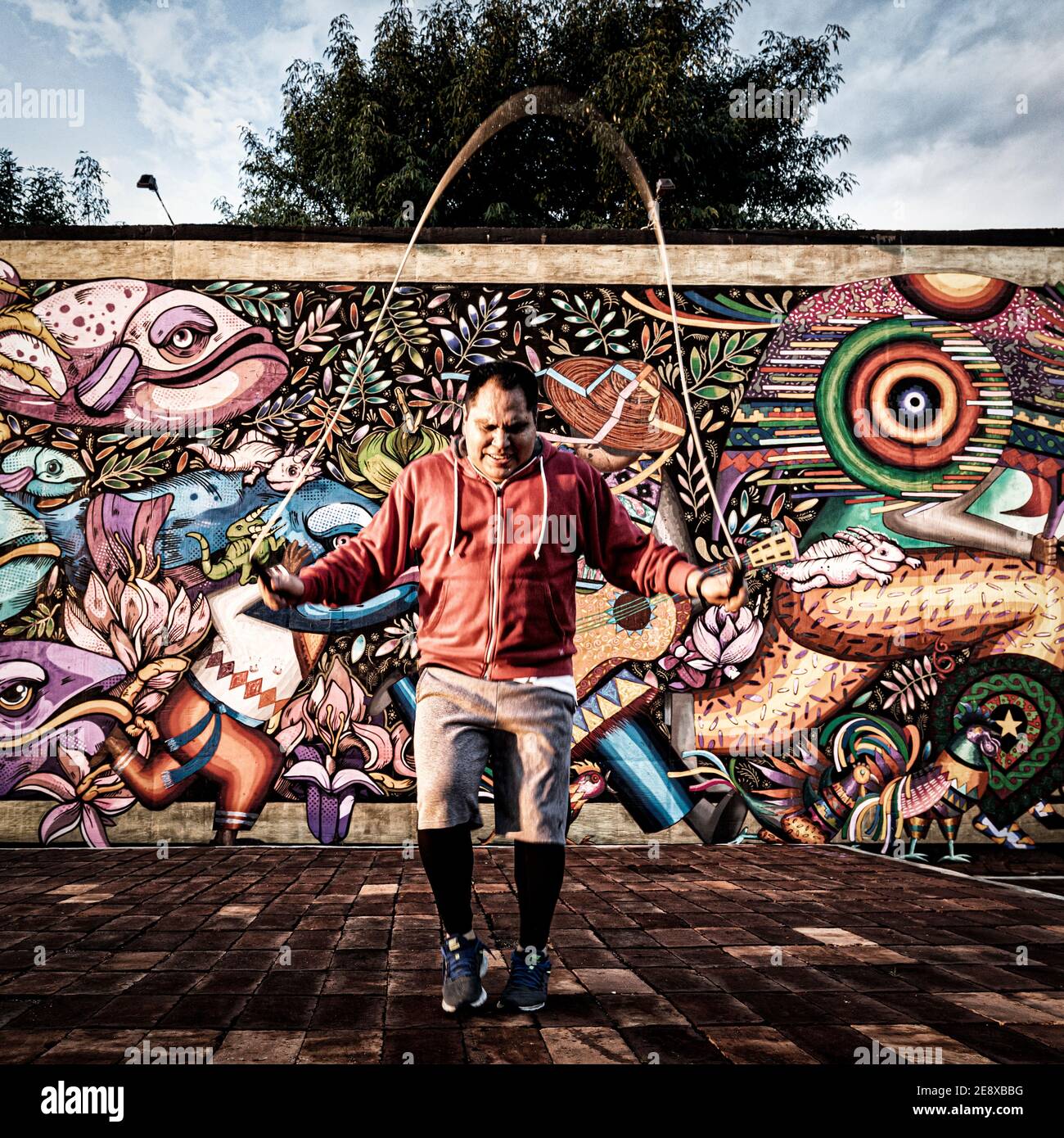 A middle aged hispanic man jumps rope near a mural in downtown Morelia, Michoacan, Mexico. Stock Photo
