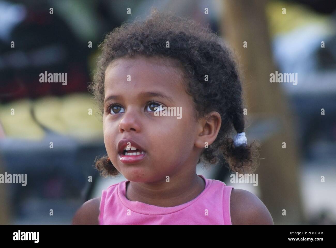 Facial emotional portrait of adorable little african american baby girl with big hazel prying eyes  looking up in curiously. Emotional face Stock Photo
