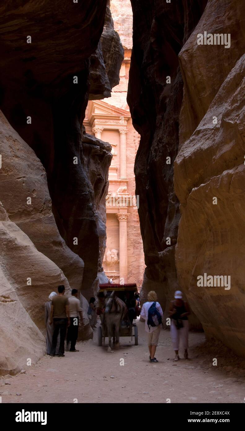 Tourist people walking at the entrance to petra monument through a rocky canyon , unesco world heritage site in Jordan Stock Photo