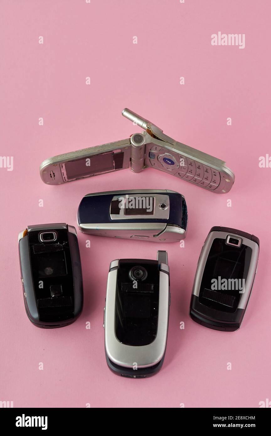 broken mobile phones, recycling technology, early 2000s on pink background and copy space,. Stock Photo