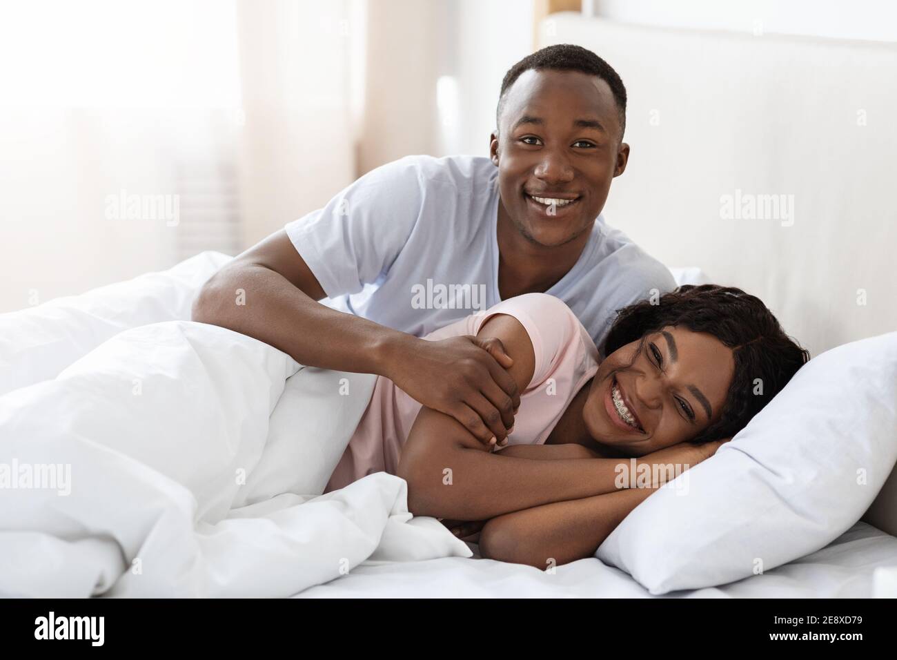 Happy black couple cuddling in bed at home Stock Photo Alamy