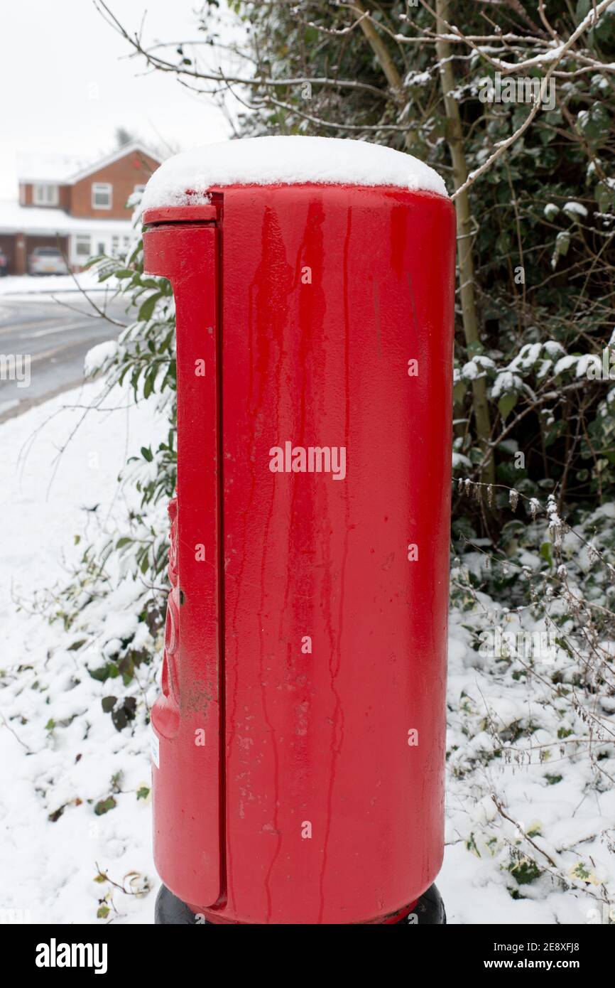 close up of British bright red royal mail box at roadside covered in snow on a cold wintery day Stock Photo