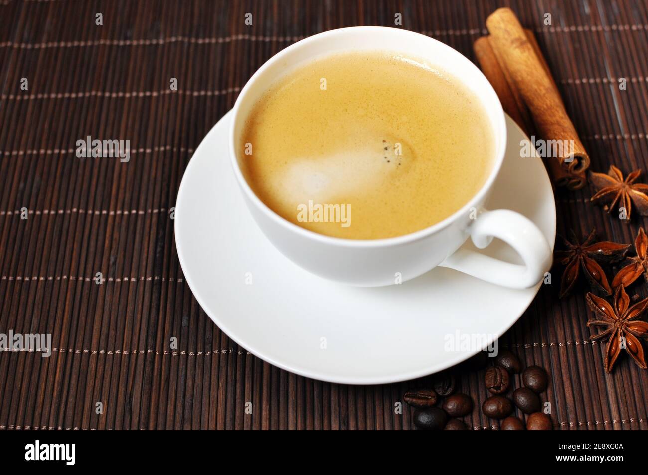 Cup of hot coffee with cinnamon and anise star decoration on brown wooden background. Top table Stock Photo