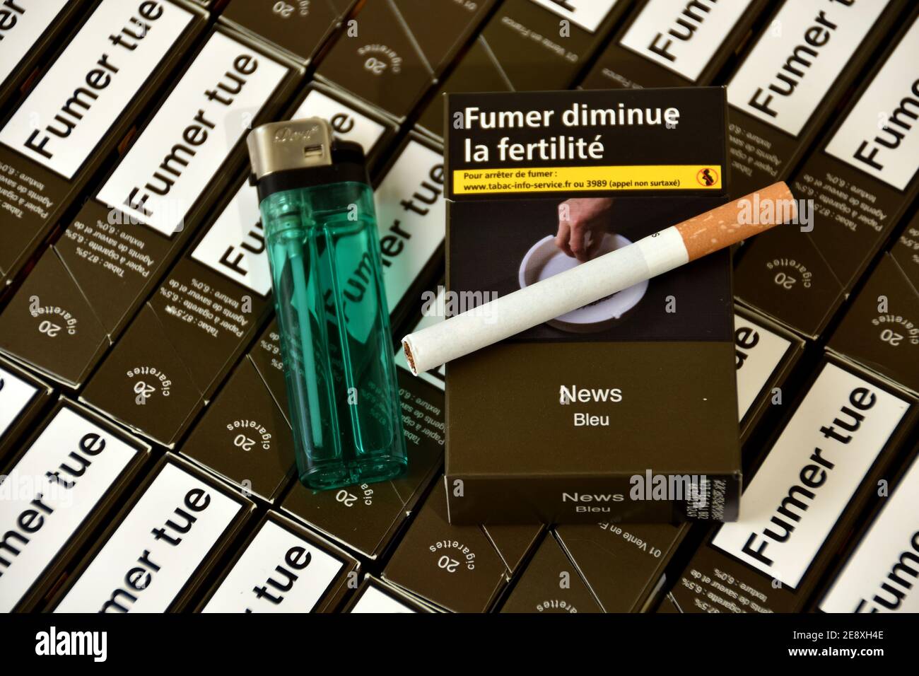 In this photo illustration a cigarette and a lighter seen displayed on packets of cigarettes