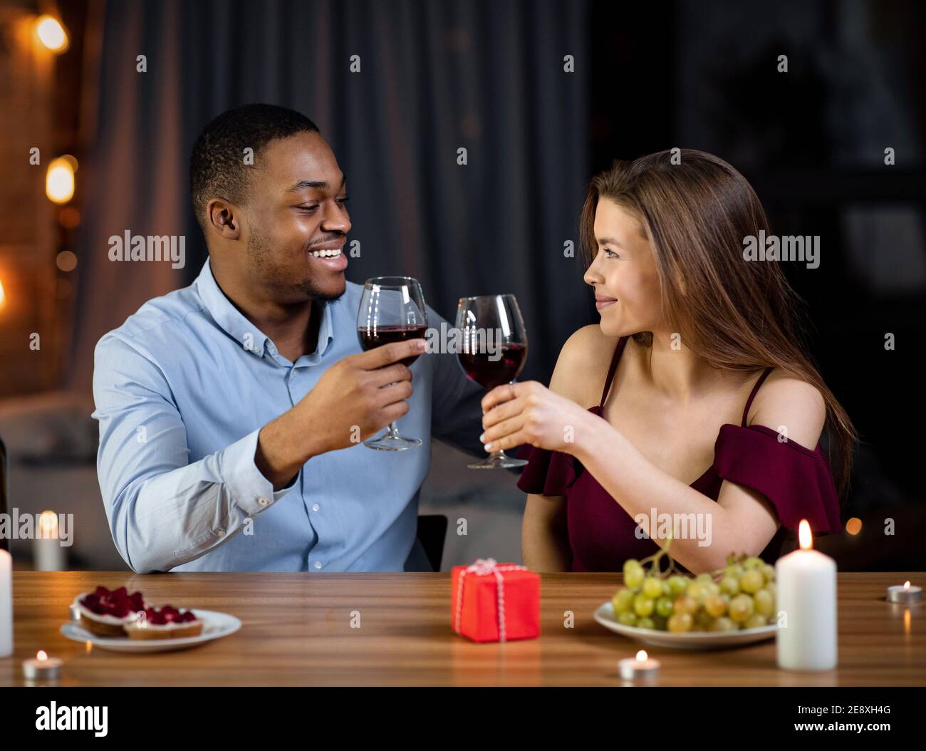 Affectionate Mixed Couple Having Romantic Dinner In Restaurant, Drinking Wine And Smiling Stock Photo