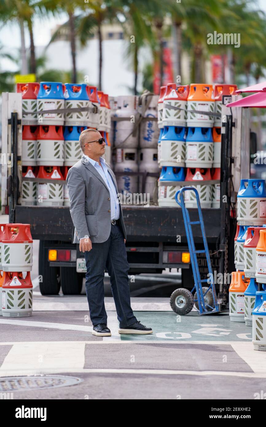 Businessman surrounded with propane canisters candid street photography Stock Photo