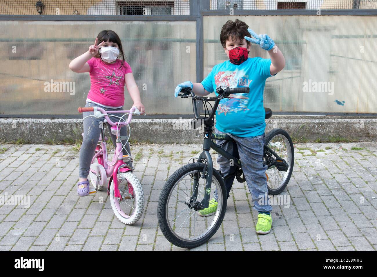 Campobasso, Molise Region, Italy: Two children make the 'everything OK' gesture while playing with their bicycles during the days coronavirus emergenc Stock Photo
