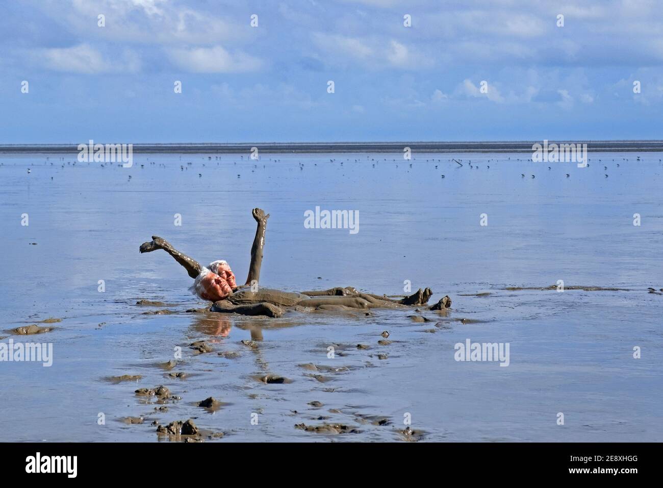 Two ederly tourists taking a mud bath on the beach in the Bigi Pan Nature Reserve in Nieuw Nickerie, Suriname / Surinam Stock Photo