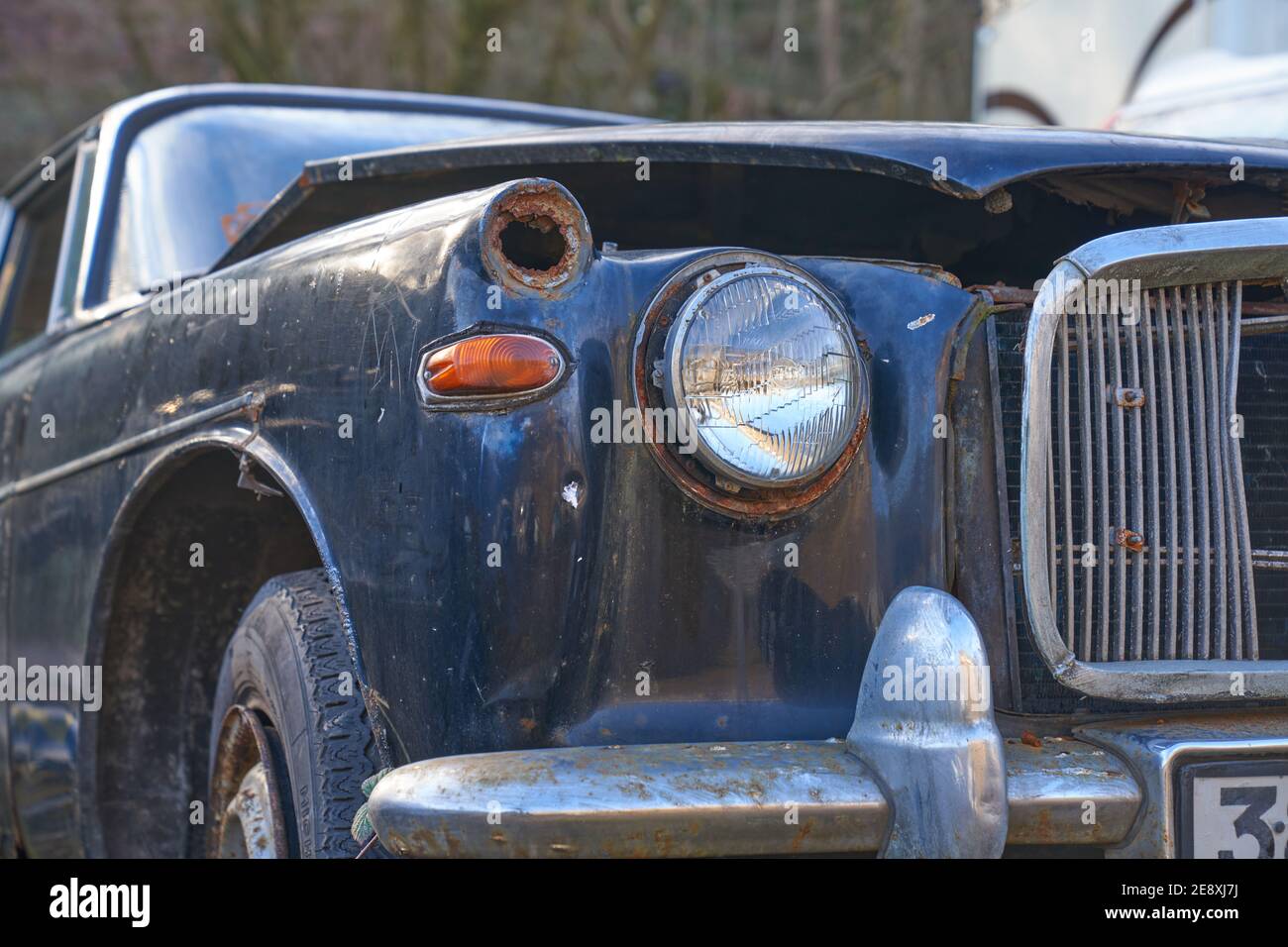Abandoned old classic blue rover that has been left outside a workshop Stock Photo