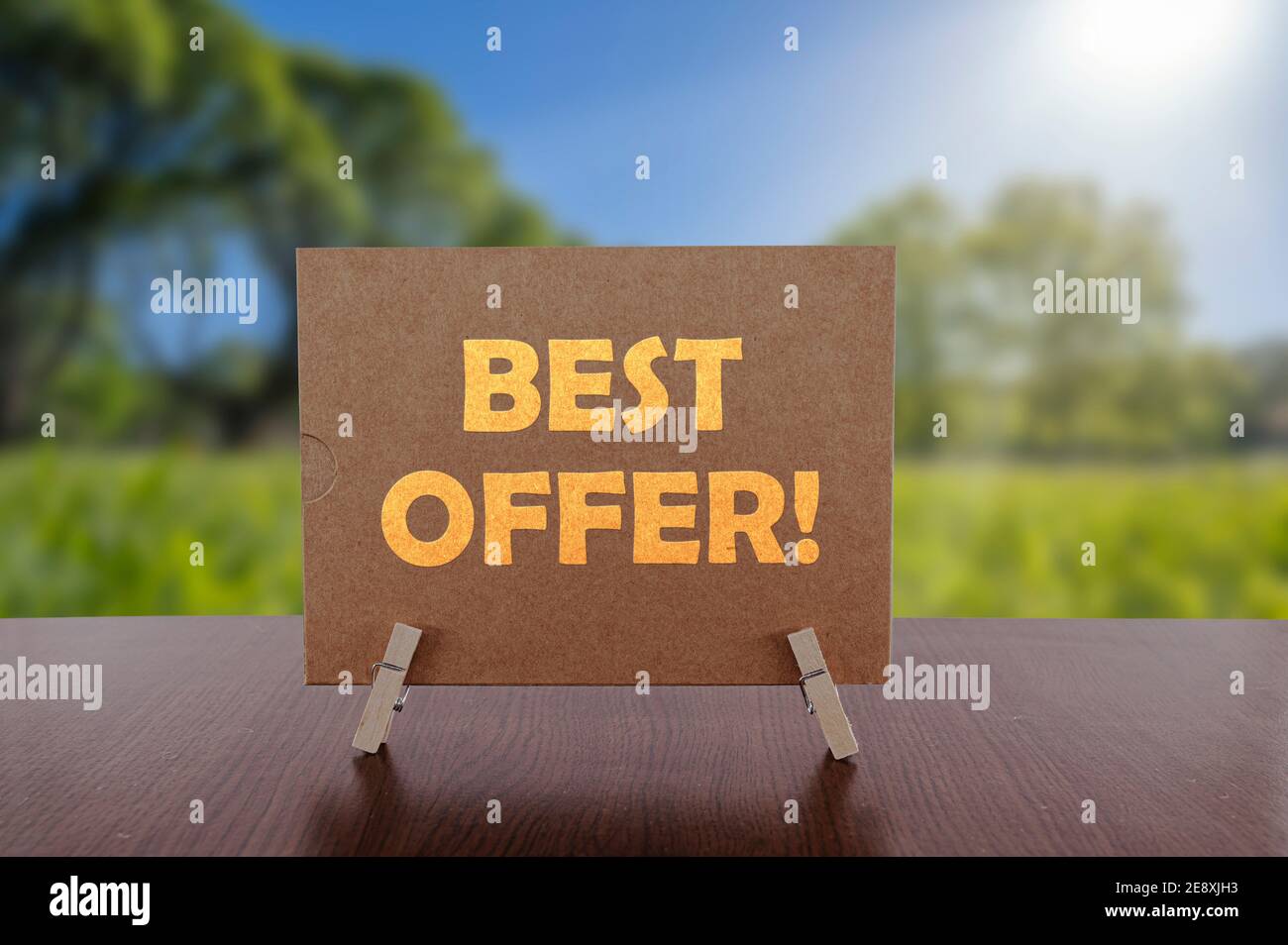 Best offer text on card on the table with sunny green park background