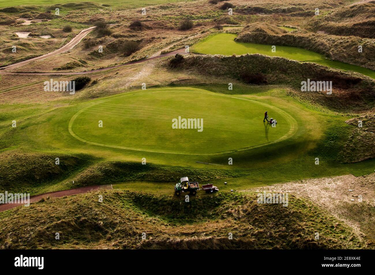 A greenskeeper at Wallasey Golf Club, Wirral mows the green during lockdown on February 1st 2021.  Golf clubs around the UK remain under strict restri Stock Photo
