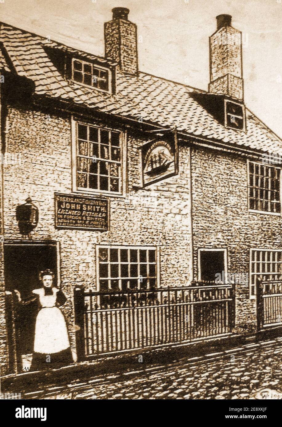 The former 'Greenland Fishery' public house in lower Church Street,  Whitby, Yorkshire, UK, with its landlady standing at the entrance -  Still in existence as a private dwelling today. Stock Photo