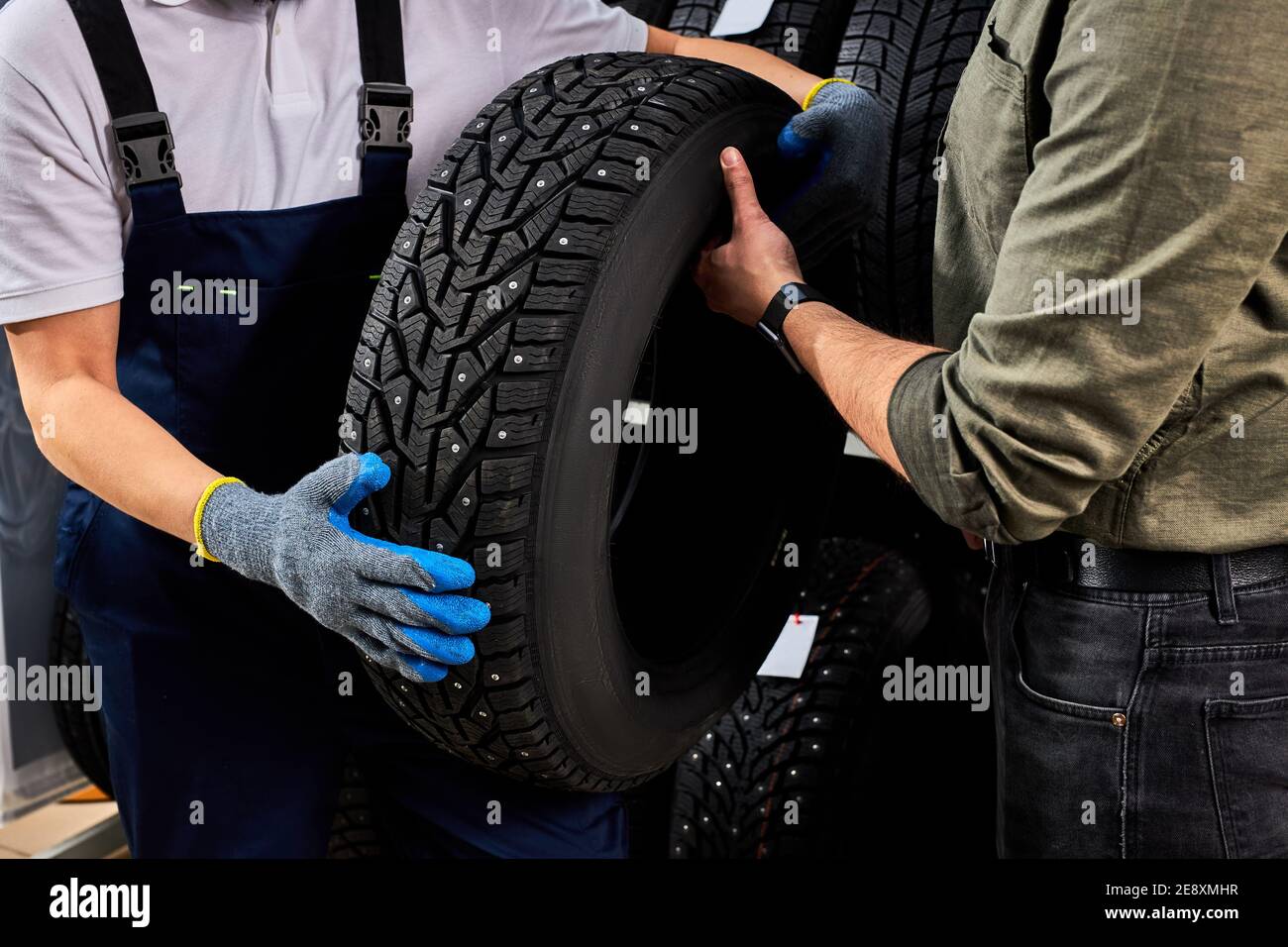 two men looking at auto tire surface discussing advantages of winter
