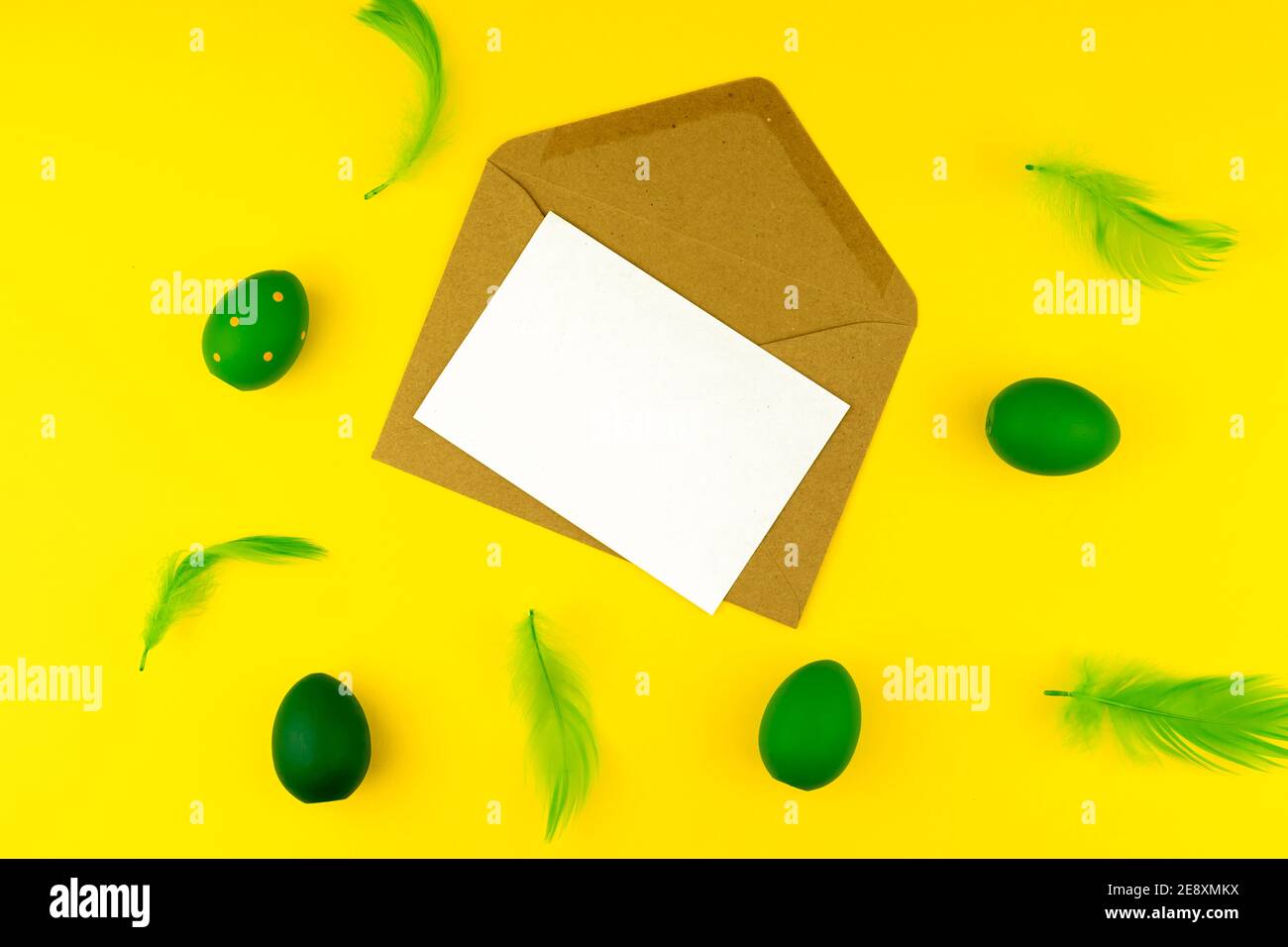 Spring Easter layout with green feathers and eggs, craft envelope and blank paper for text Stock Photo