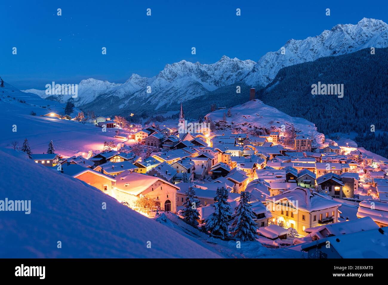 Traditional alpine village of Ardez covered with snow at dusk, canton of Graubunden, Engadine, Switzerland Stock Photo