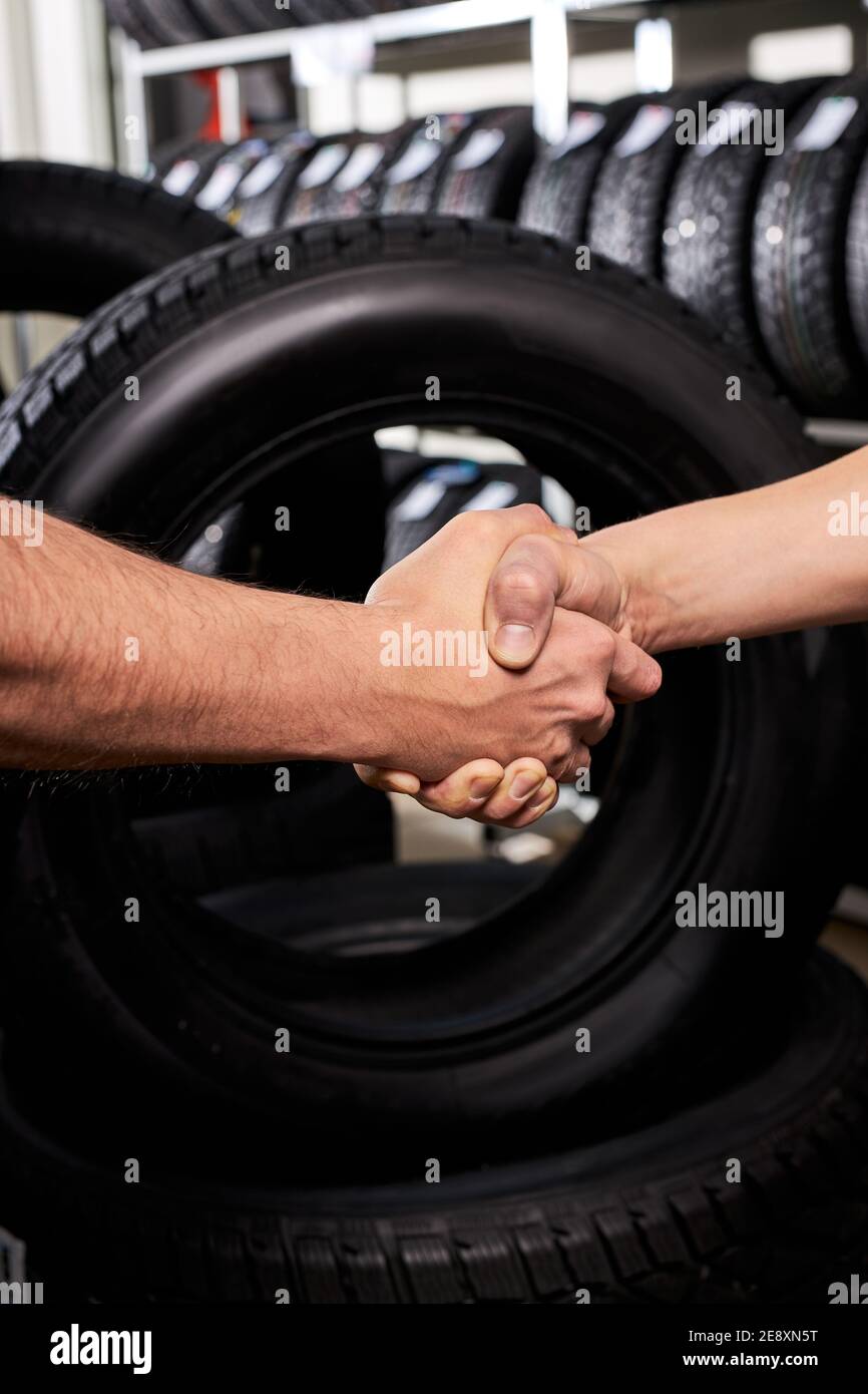 salesman and customer shaking hands in auto service shop, male made