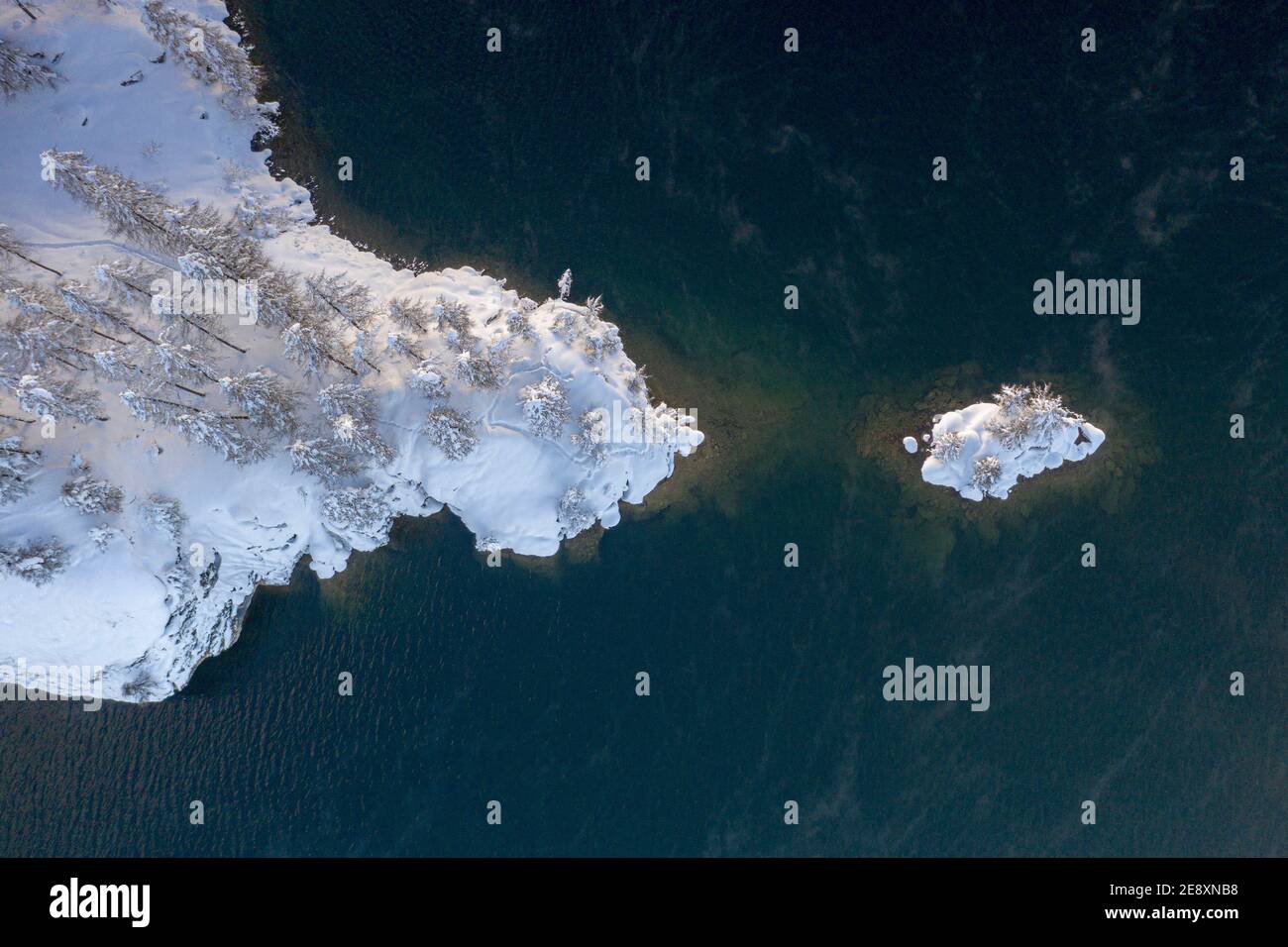 Aerial view of frozen islet and snowy woods on shore of icy Lake Sils, Switzerland Stock Photo