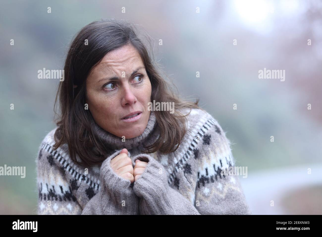 Scared adult woman looking at side walking alone in a park Stock Photo