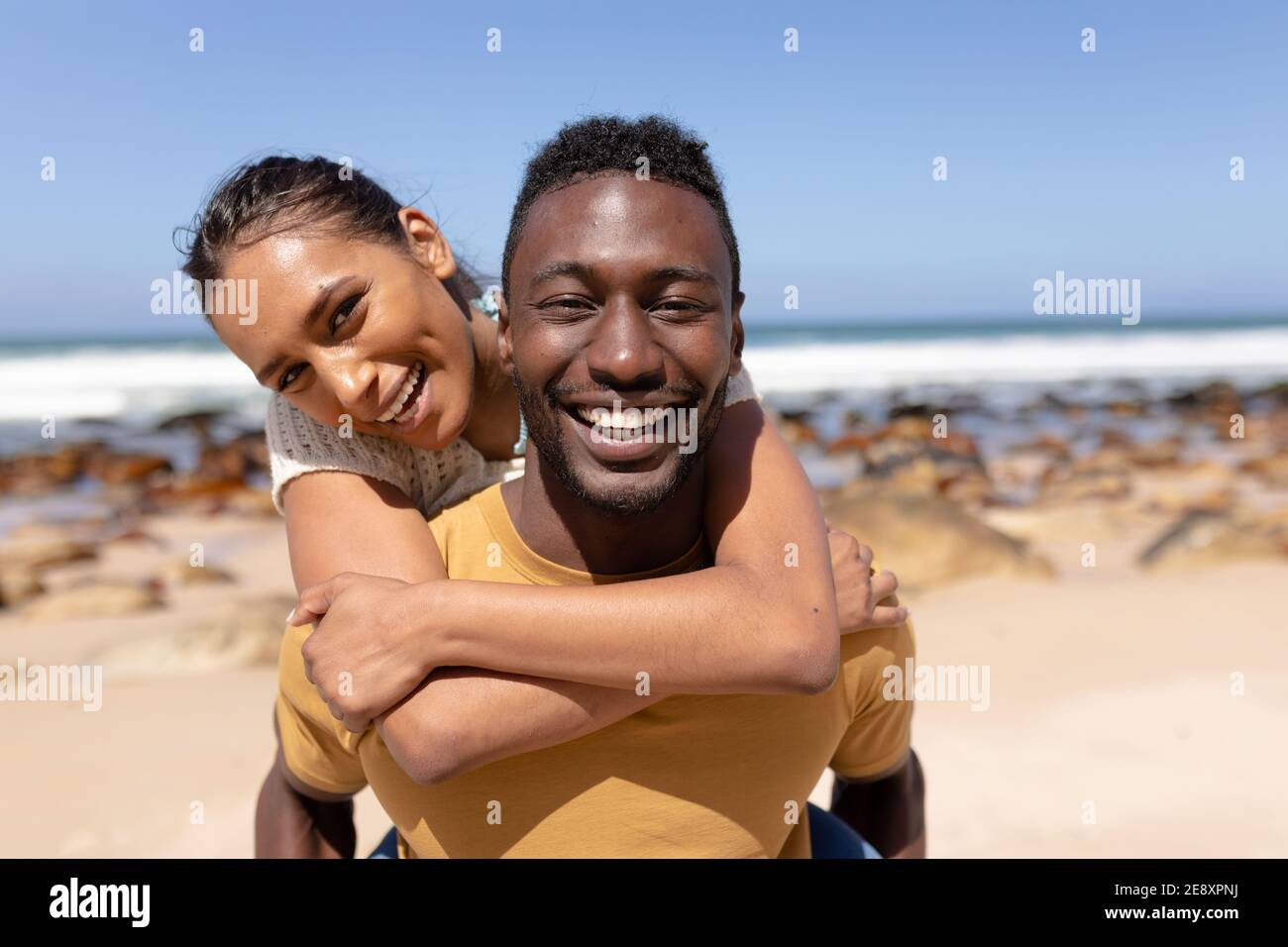 Portrait of african american couple embracing on a beach by the sea ...