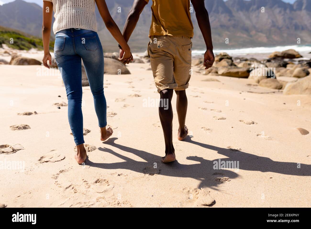 African american couple walking holding hands on a beach by the sea ...