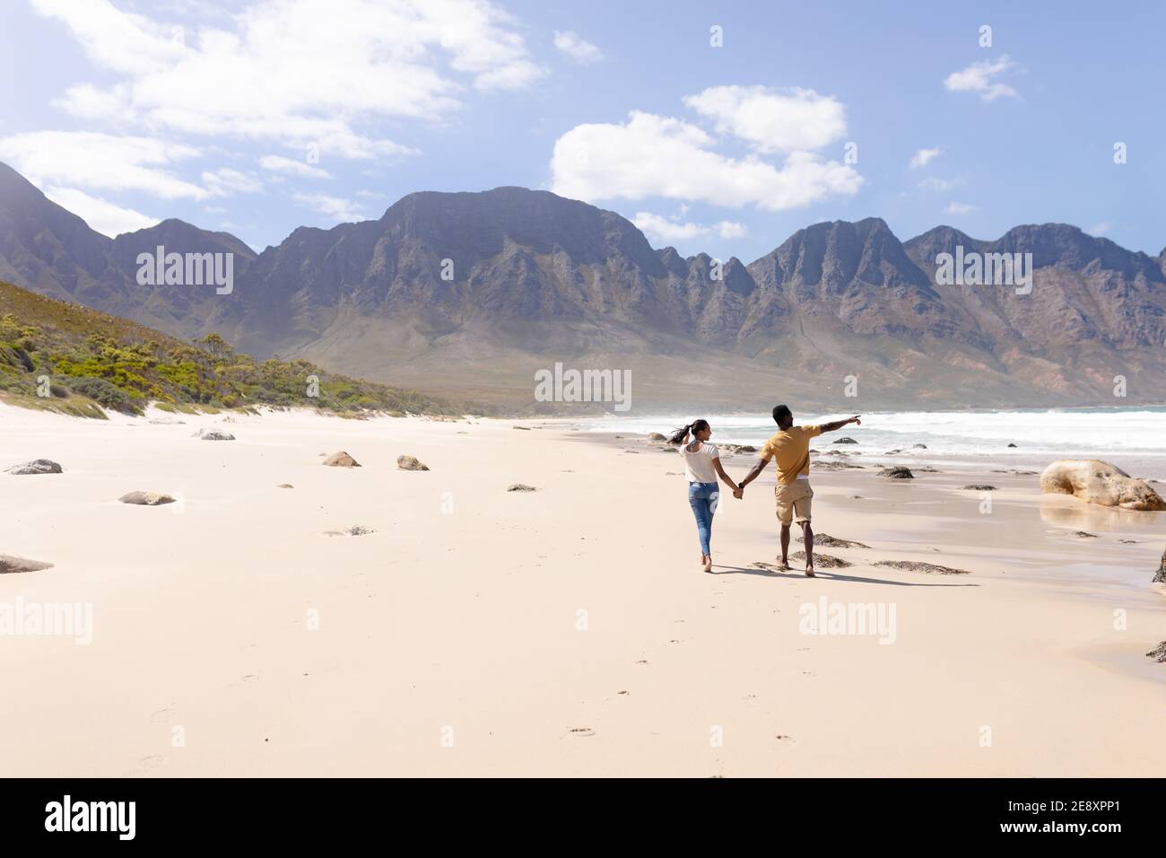 African american couple walking holding hands on a beach by the sea ...