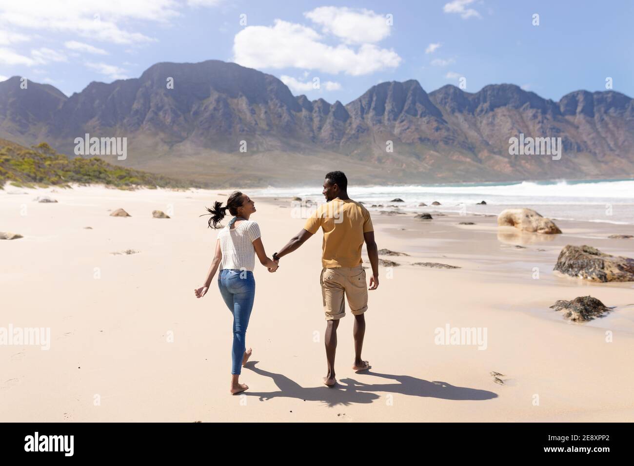 African american couple walking holding hands on a beach by the sea ...